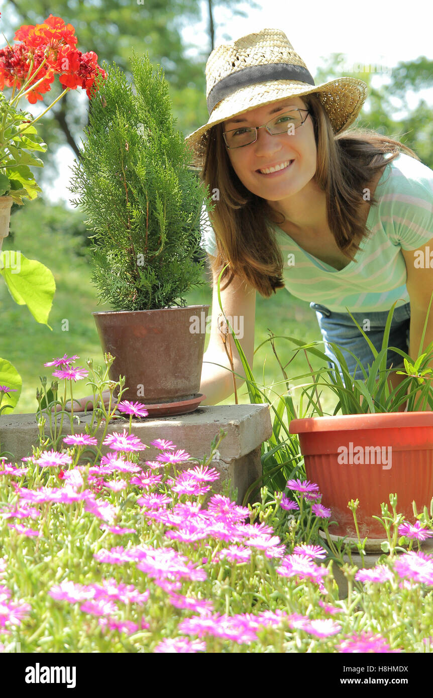 Giovane donna lavora con fiori nel giardino Foto Stock