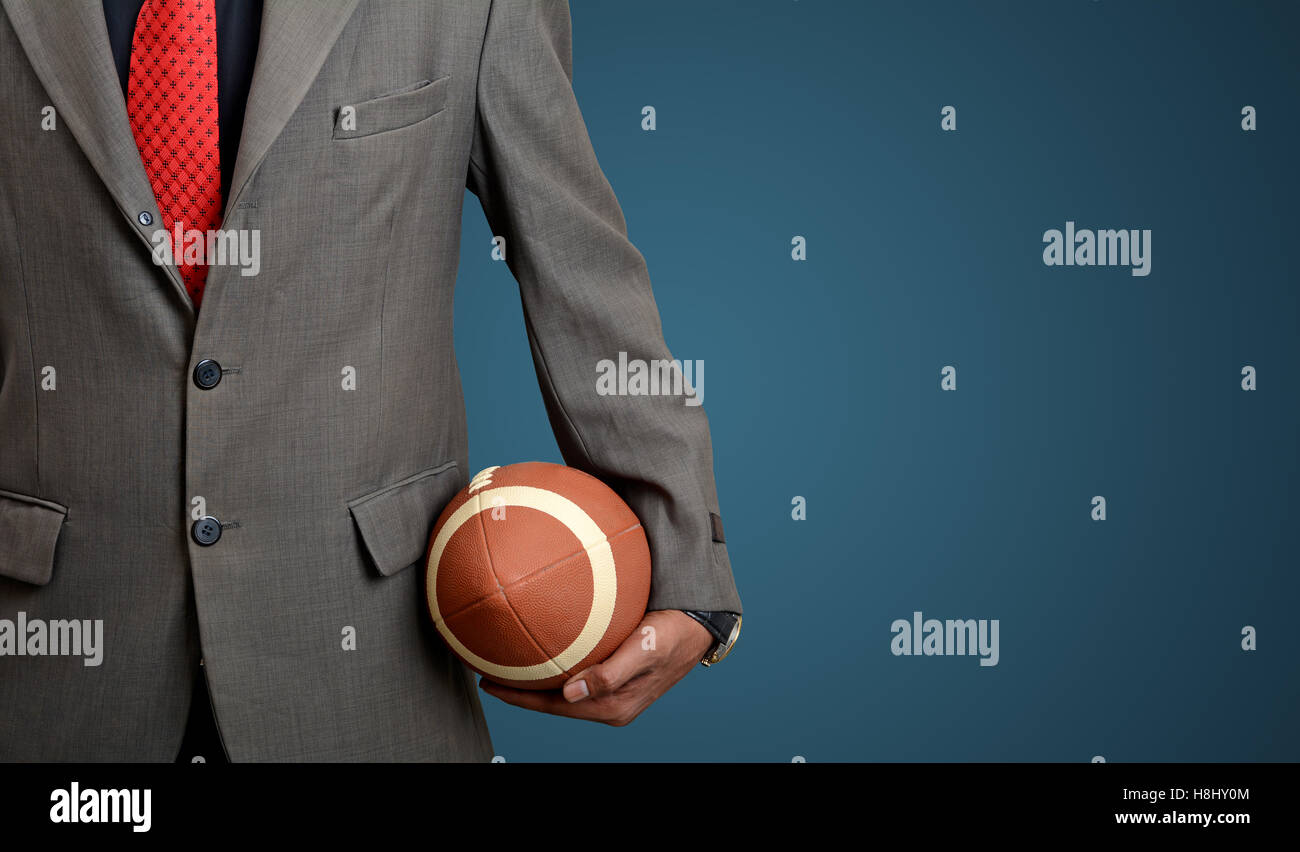 Professional adatta l uomo con il football americano palla sul banner blu sullo sfondo. Foto Stock