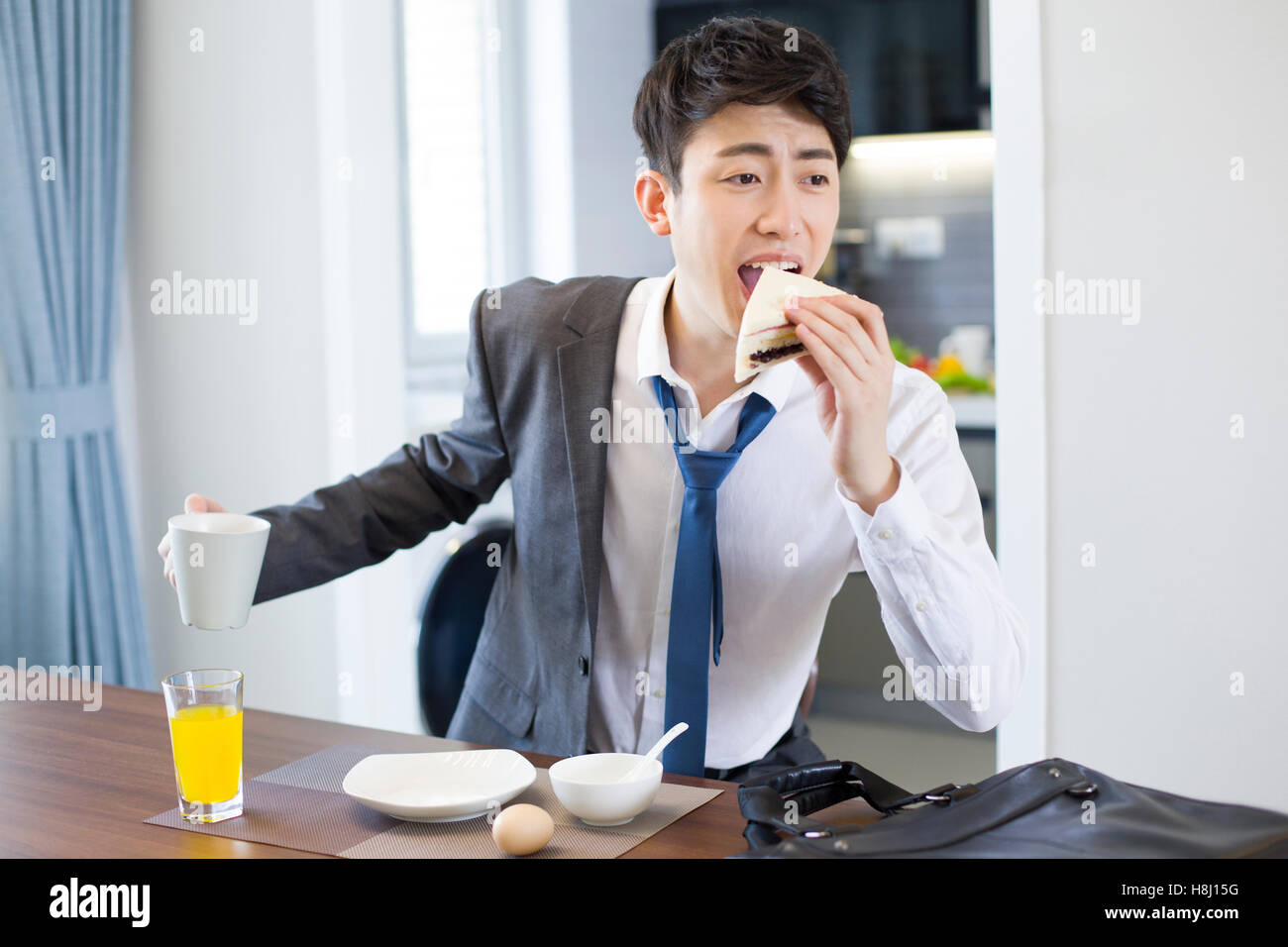 Giovane imprenditore cinese di avere la prima colazione in una fretta Foto Stock