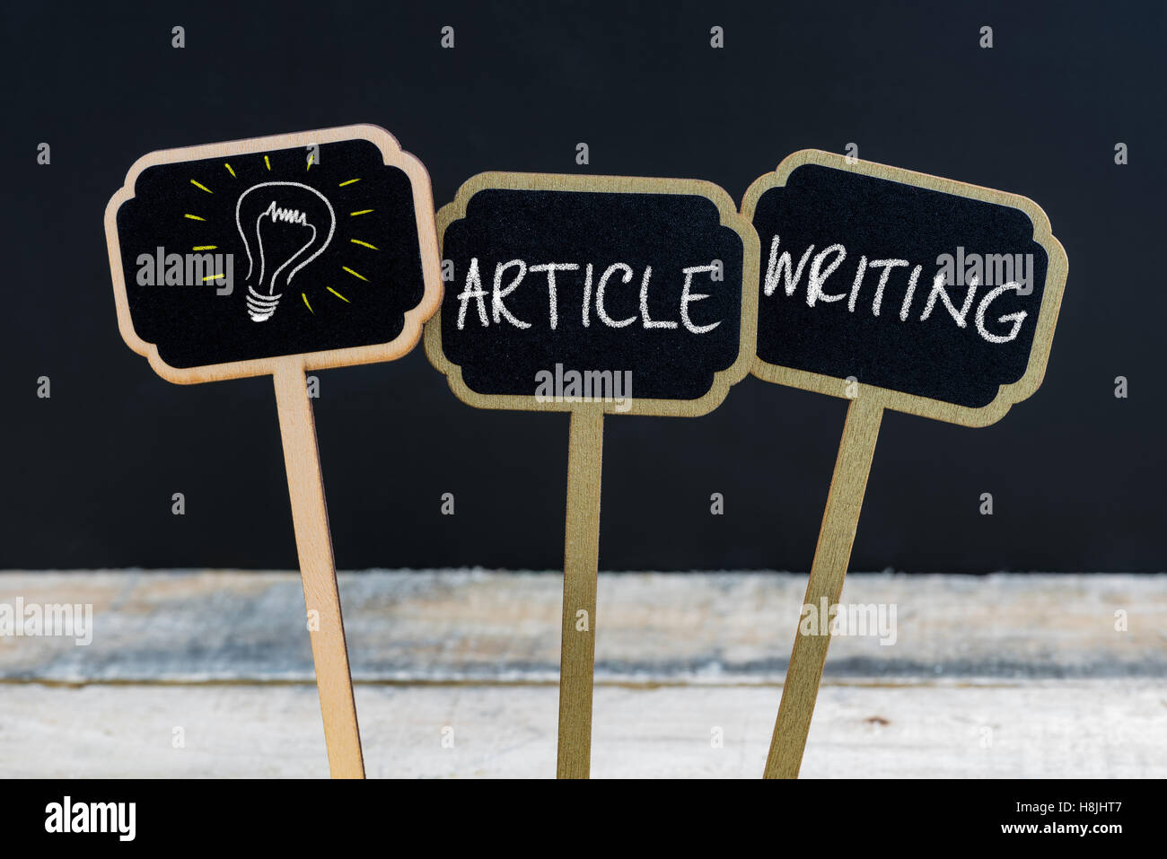 Messaggio di concetto articolo la scrittura e la lampadina della luce come simbolo per idea scritto con un gessetto su legno mini etichette di Blackboard Foto Stock