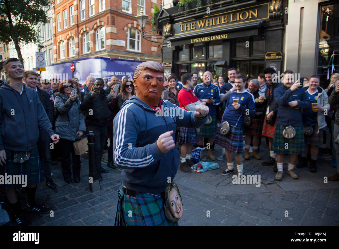 Scozia ventole di cui uno con un Donald Trump maschera in stato d'animo gioioso bere e cantare insieme a Covent Garden davanti a loro partita di calcio, Inghilterra vs Scozia, World Cup qualificatori di stadio di gruppo il 11 novembre 2016 a Londra, Regno Unito. Home International la rivalità tra le loro rispettive squadre nazionali è il più antico attrezzo internazionale nel mondo, in primo luogo ha svolto nel 1872. Foto Stock