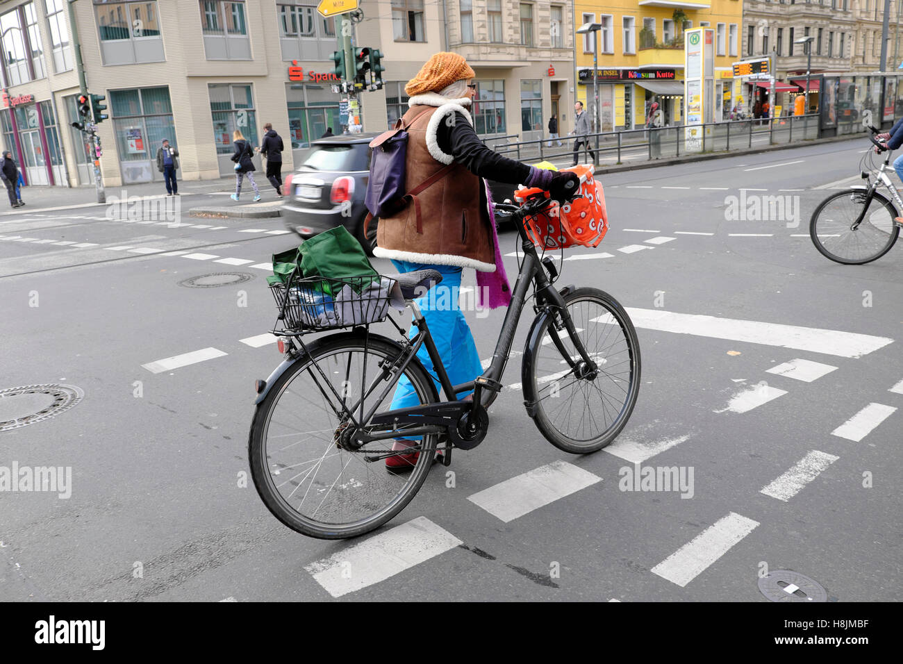 Donna anziana camminare vicino a metropolitana di Eberswalder Straße station con la bicicletta e shopping in cesti in autunno abbigliamento Berlino KATHY DEWITT Foto Stock