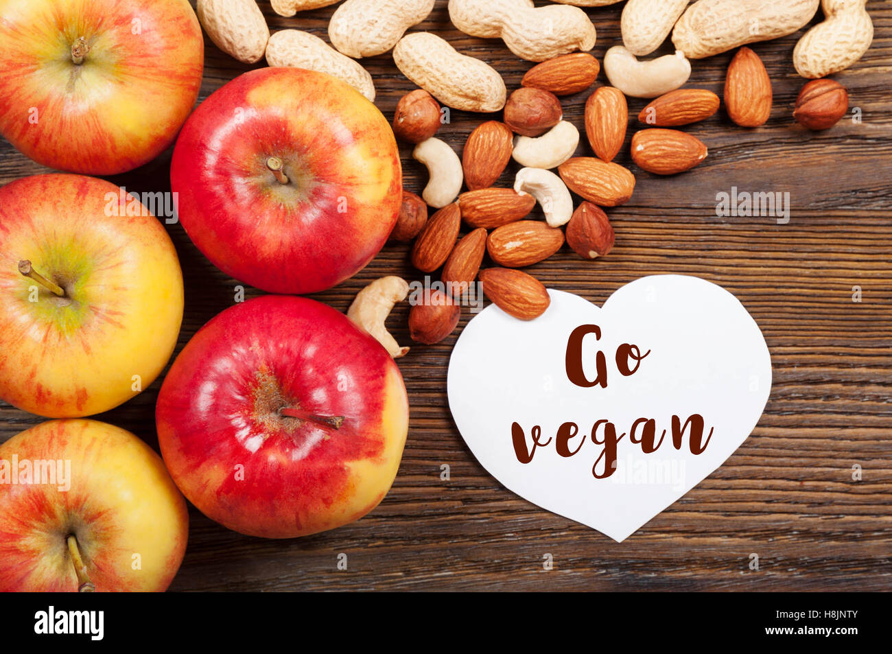 Mature mele rosse e i dadi su uno sfondo di legno. Vista dall'alto. Concetto vegan. Foto Stock