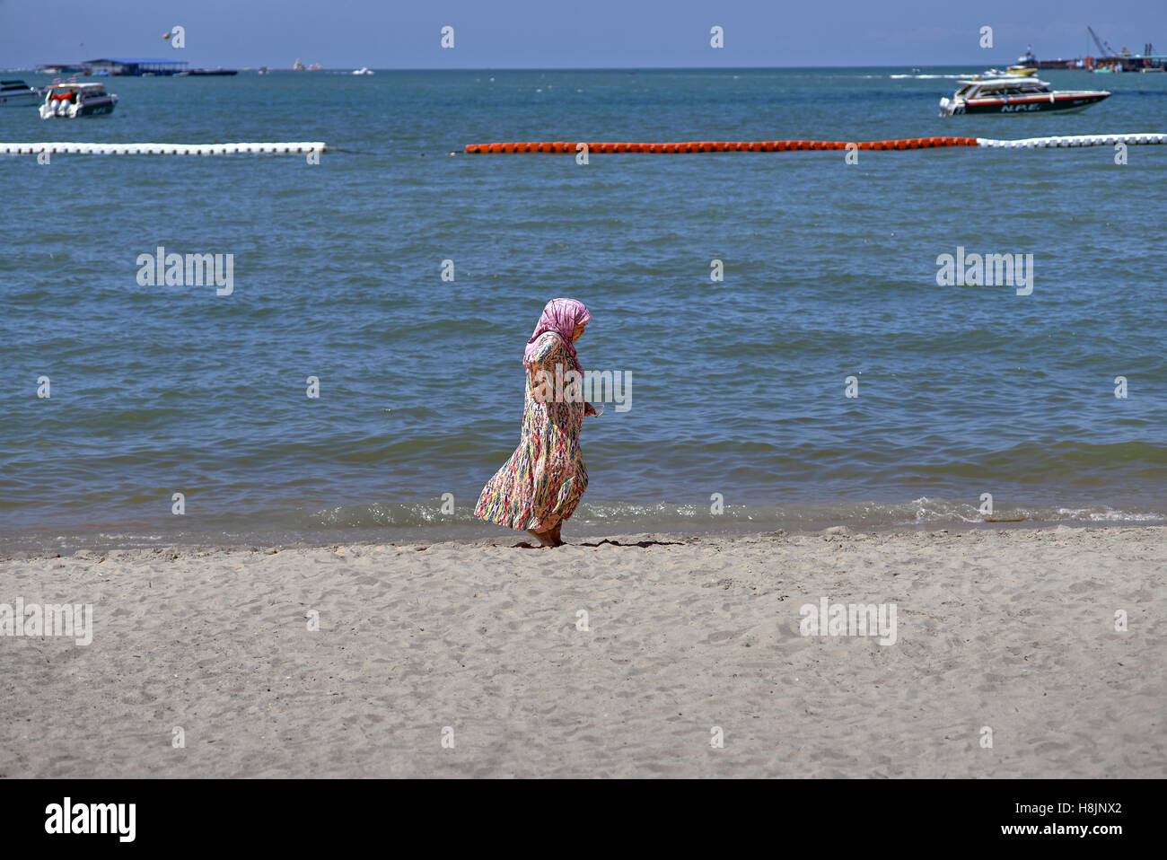 Donna spiaggia da sola. Donna Medio Oriente a piedi lungo la spiaggia a Pattaya Thailandia S. E. Asia Foto Stock