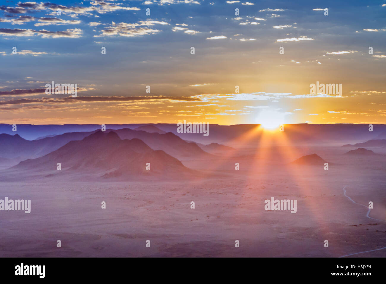 Alba con i soli raggi fa capolino oltre l'orizzonte in Sossusvlei Namibia dando un aspetto lunare al paesaggio Foto Stock