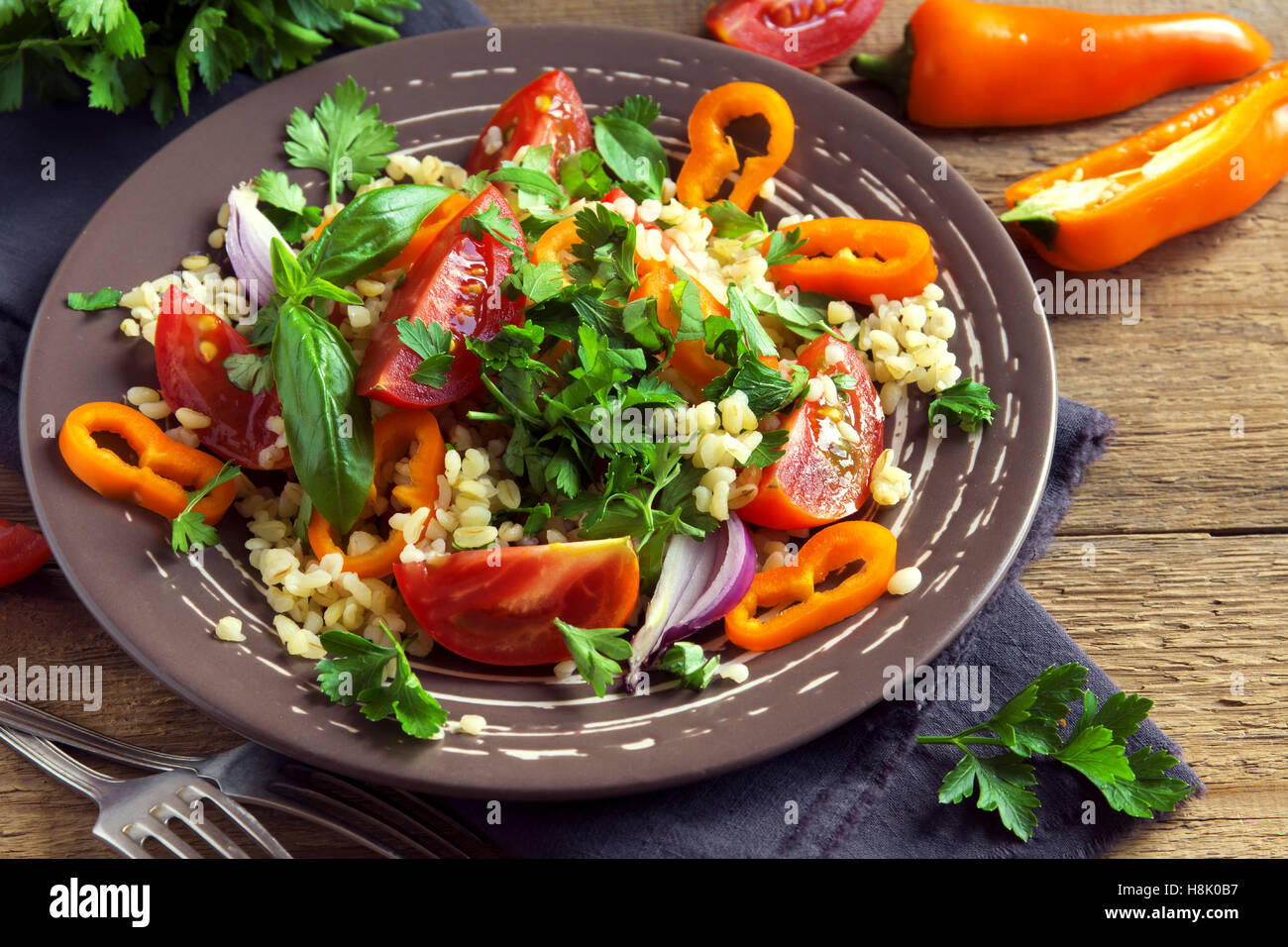Fresco di pomodoro organico e il couscous con insalata di verdure e verdi - sana insalata vegetariana sulla piastra rustico close up Foto Stock