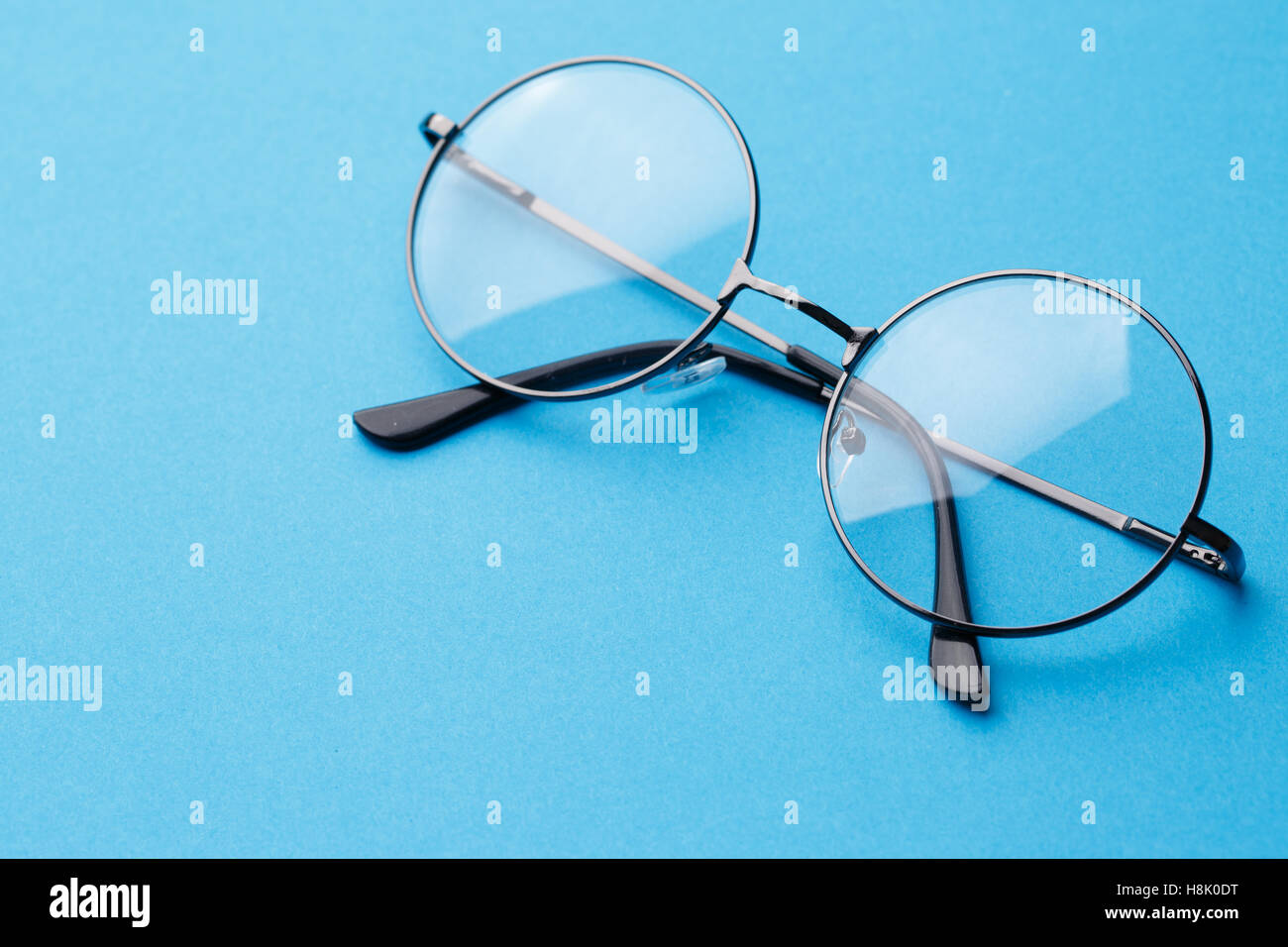 Round occhiali con lenti trasparenti sul puro sfondo blu Foto Stock