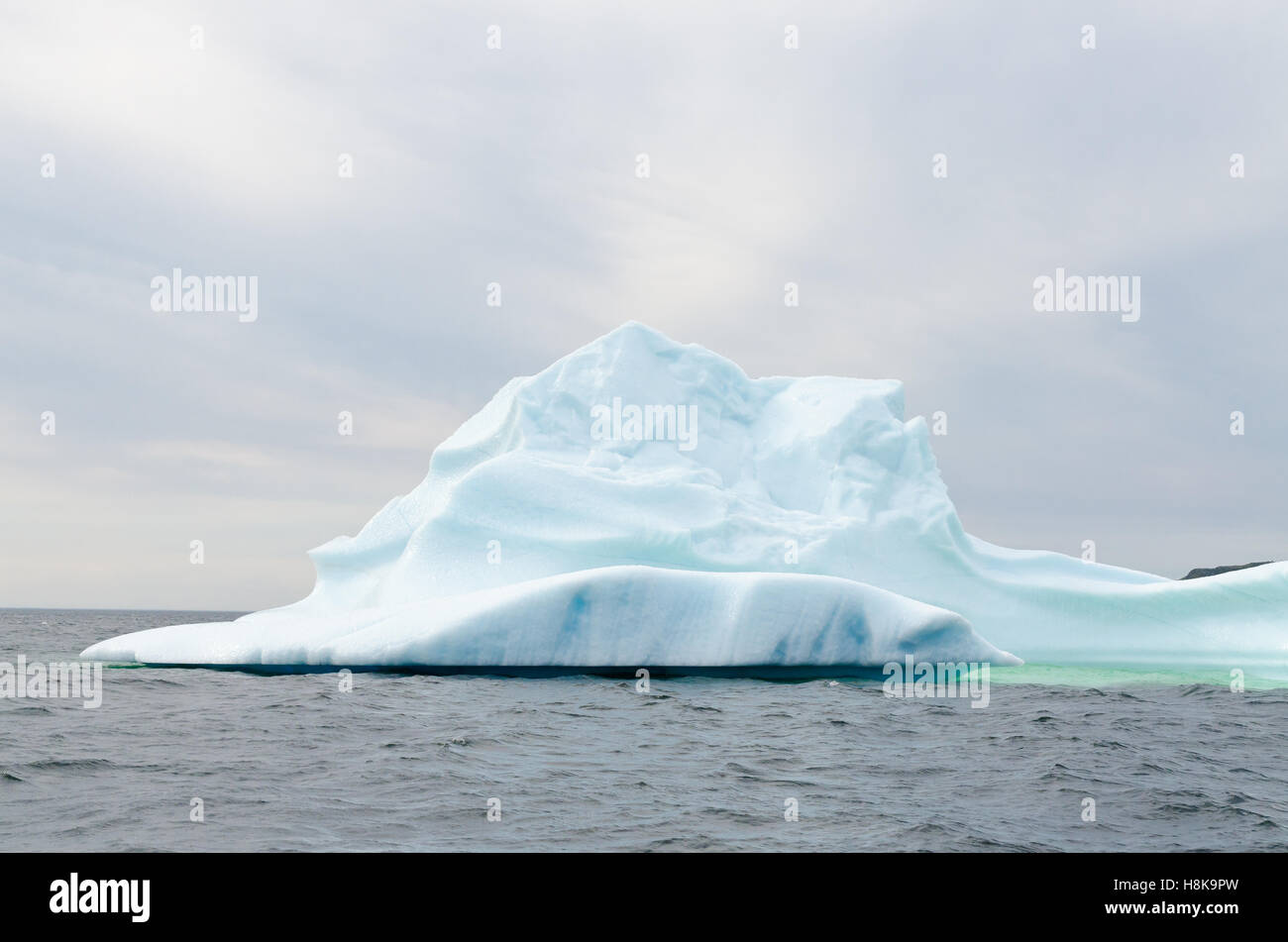 Bianco brillante iceberg sull' acqua scura e sfondo rock Foto Stock