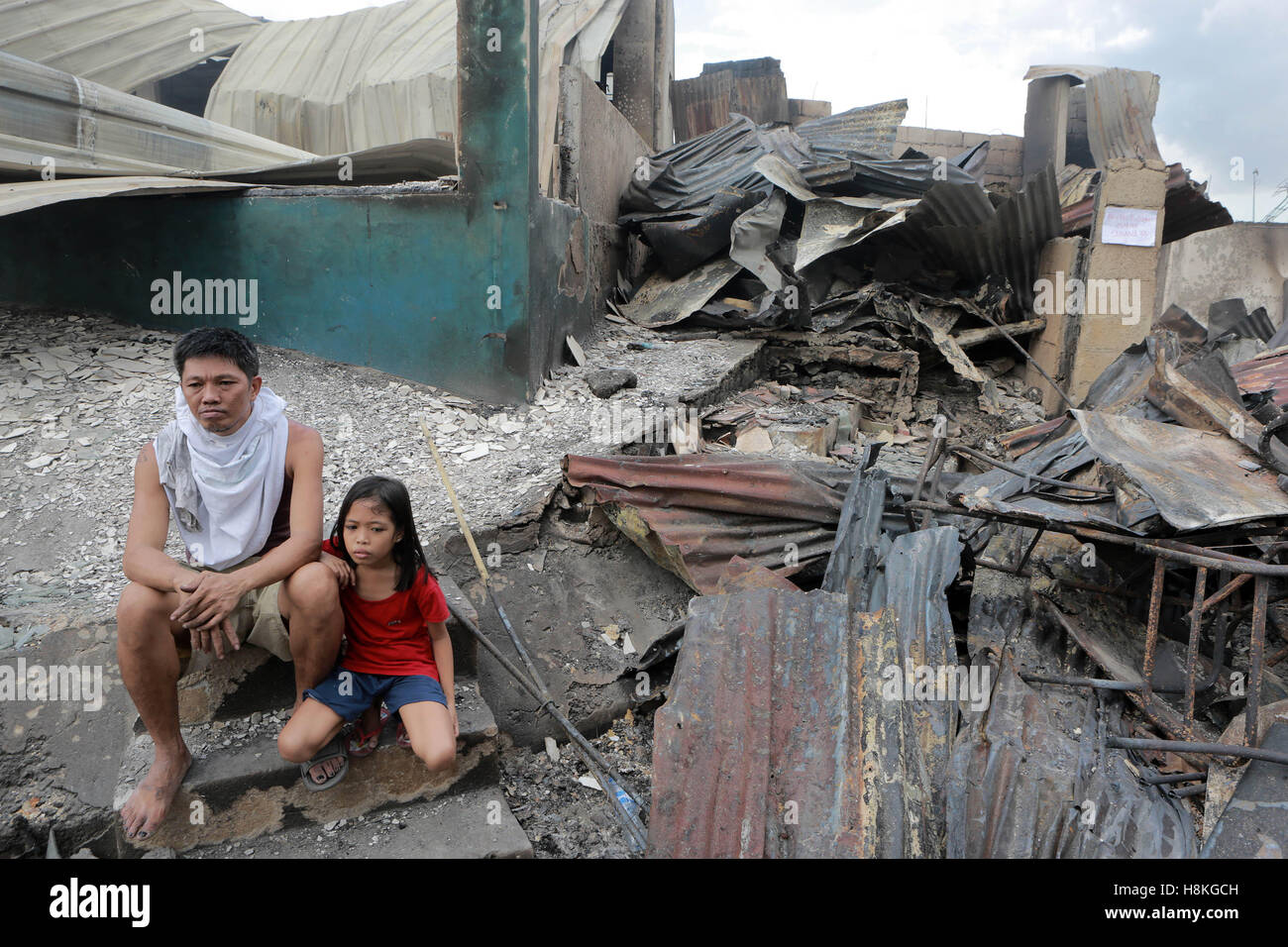 Mandaluyong, Filippine. Xiv Nov, 2016. Un padre e sua figlia sedersi davanti alla loro casa bruciata dopo un incendio in una zona residenziale di Mandaluyong, Filippine, nov. 14, 2016. Due persone sono morte mentre oltre 6 mila persone sono rimaste senza tetto nel fuoco. Credito: Rouelle Umali/Xinhua/Alamy Live News Foto Stock