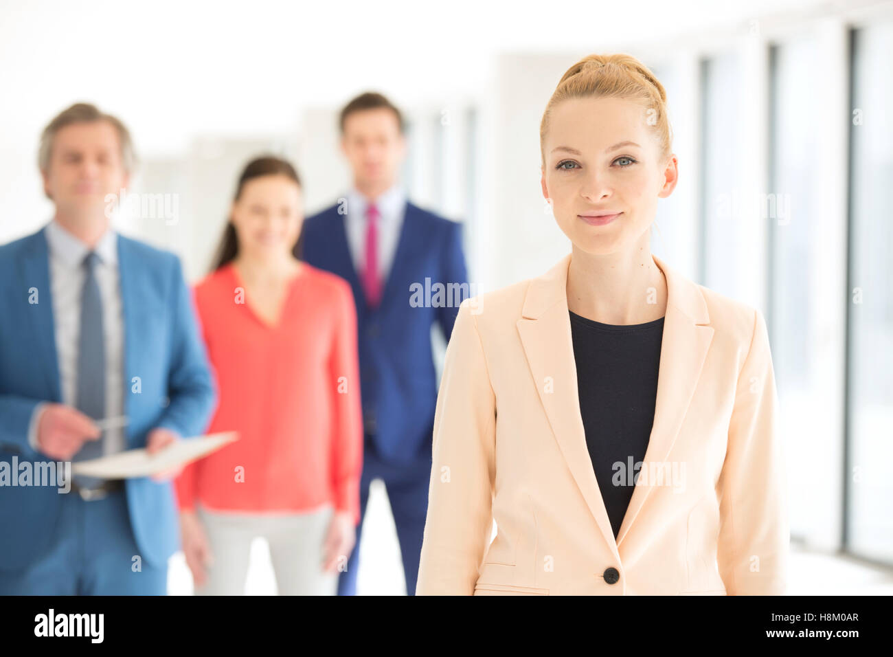 Ritratto di fiducioso imprenditrice con colleghi in background in ufficio Foto Stock
