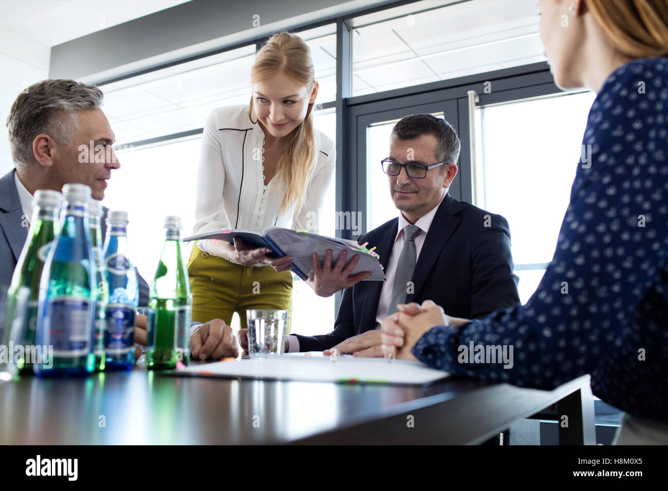 Giovane imprenditrice che mostra progetto per imprenditore durante la riunione in ufficio Foto Stock