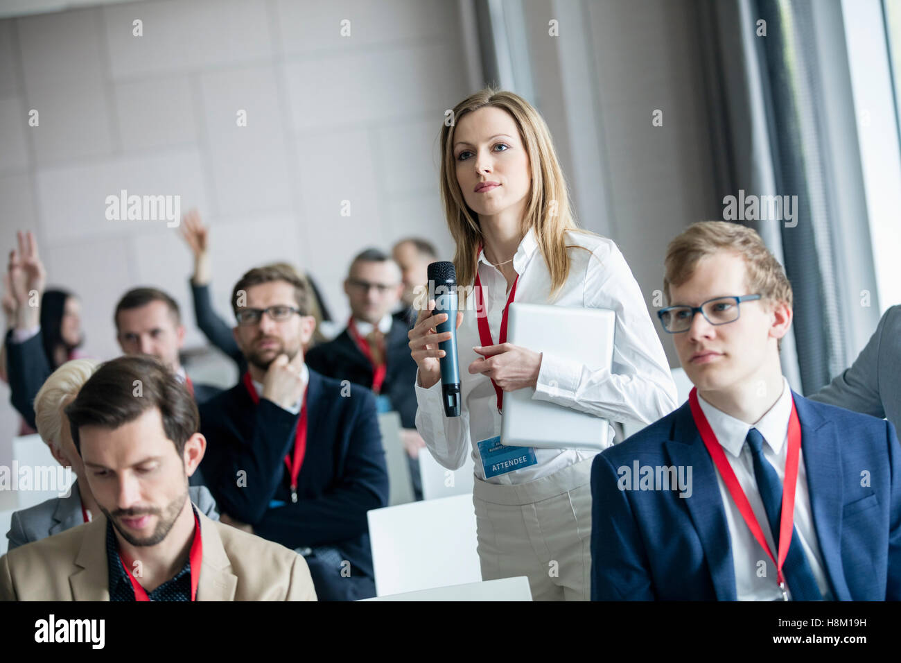 Fiducioso imprenditrice tenendo il microfono mentre ponendo domande durante il seminario Foto Stock