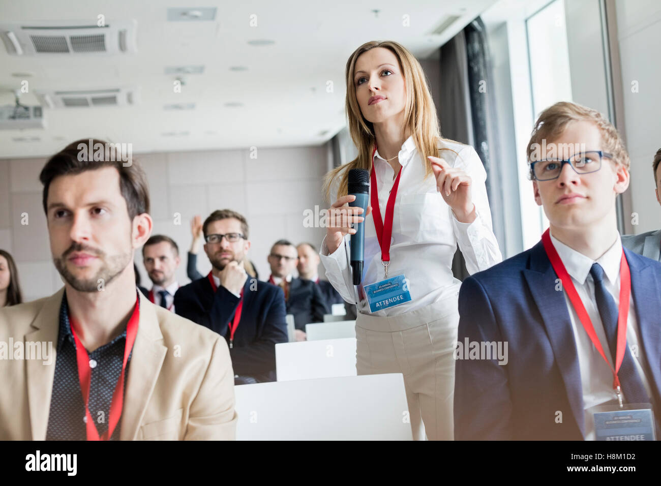Fiducioso imprenditrice gesticolando mentre si tiene il microfono durante il seminario Foto Stock