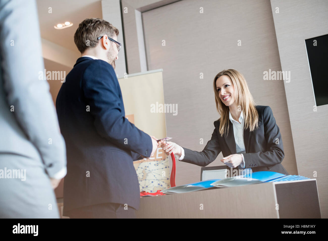 Receptionist dando carta di identità ai proprietari al convention center Foto Stock