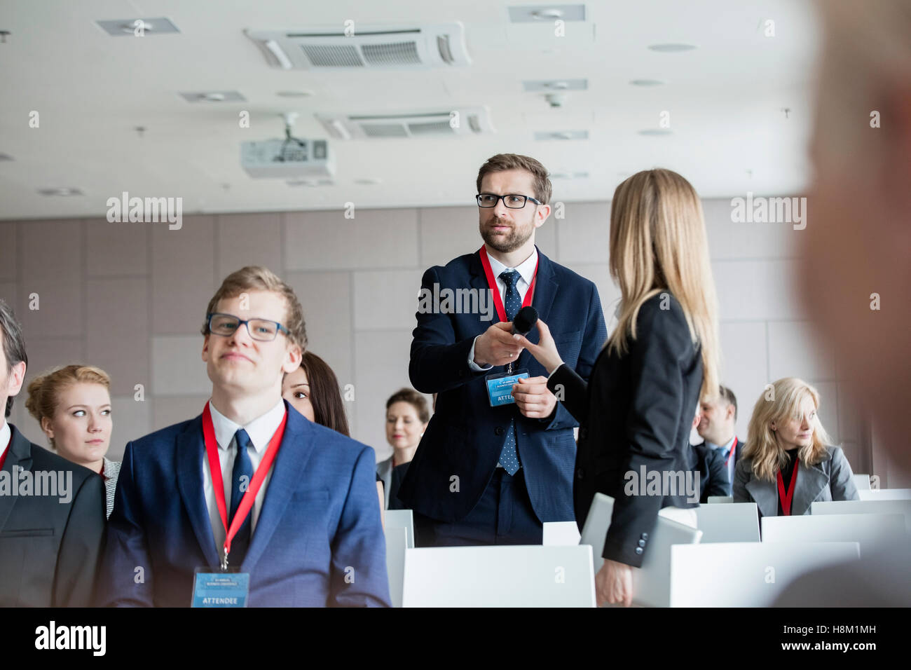La gente di affari tenendo il microfono mentre in piedi durante il seminario Foto Stock