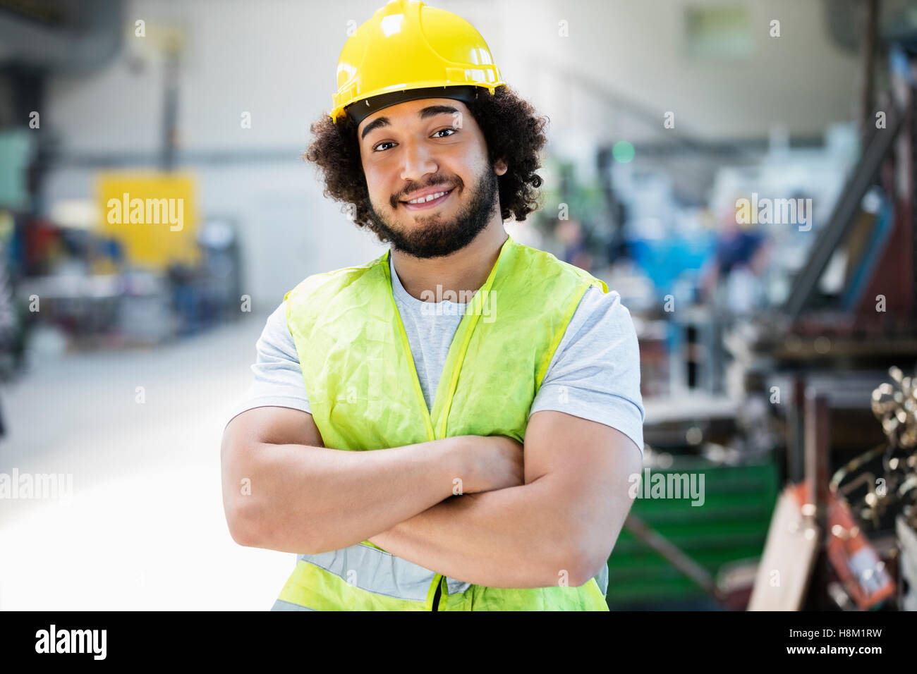Ritratto di sorridere maschio lavoratore manuale in piedi con le braccia incrociate nell'industria Foto Stock