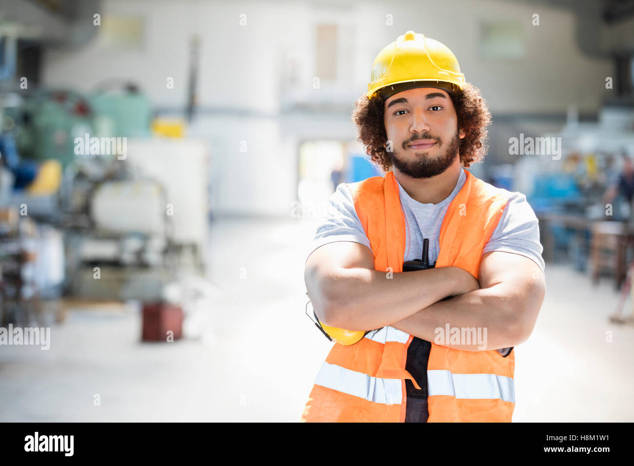 Ritratto di giovane lavoratore manuale in piedi con le braccia incrociate nella industria del metallo Foto Stock