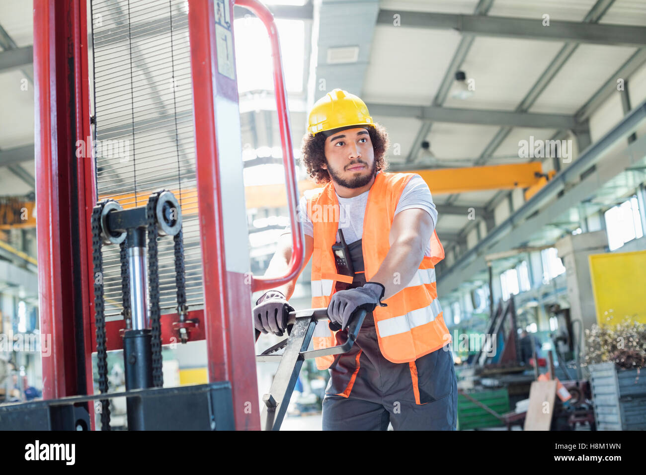 Giovane lavoratore manuale spingendo il carrello a mano nella industria del metallo Foto Stock
