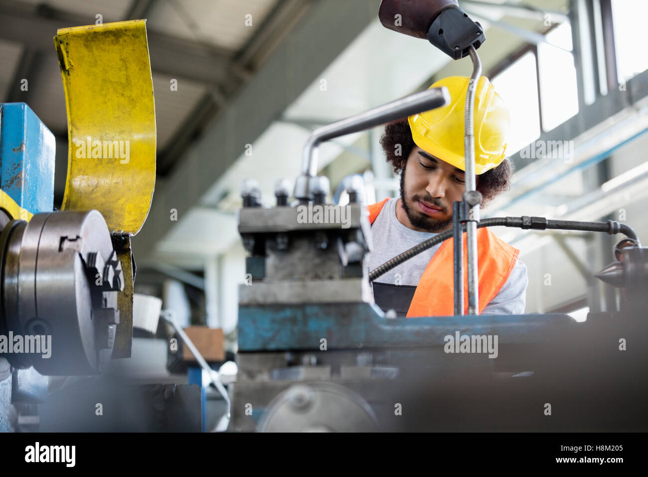 Basso angolo vista del giovane lavoratore manuale lavora su macchinari nel settore metalmeccanico Foto Stock