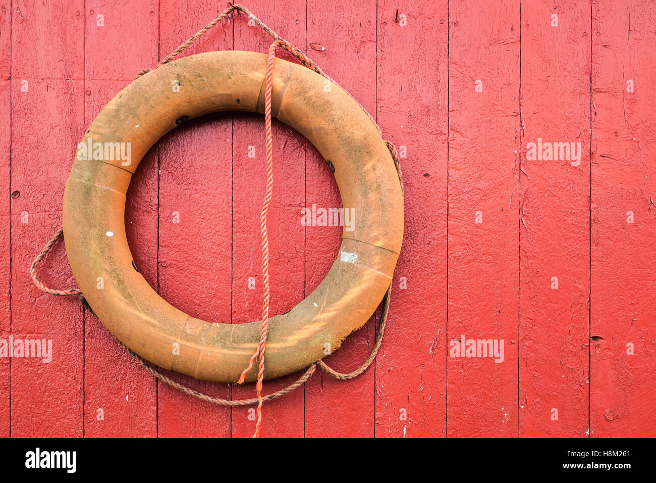 Vecchio salvagente arancione appeso sul rosso parete in legno in Norvegia Foto Stock