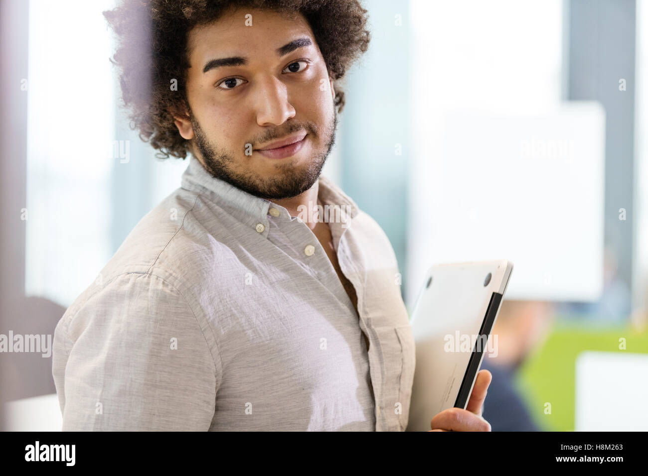 Ritratto di fiducioso giovane imprenditore tenendo il portatile in ufficio Foto Stock