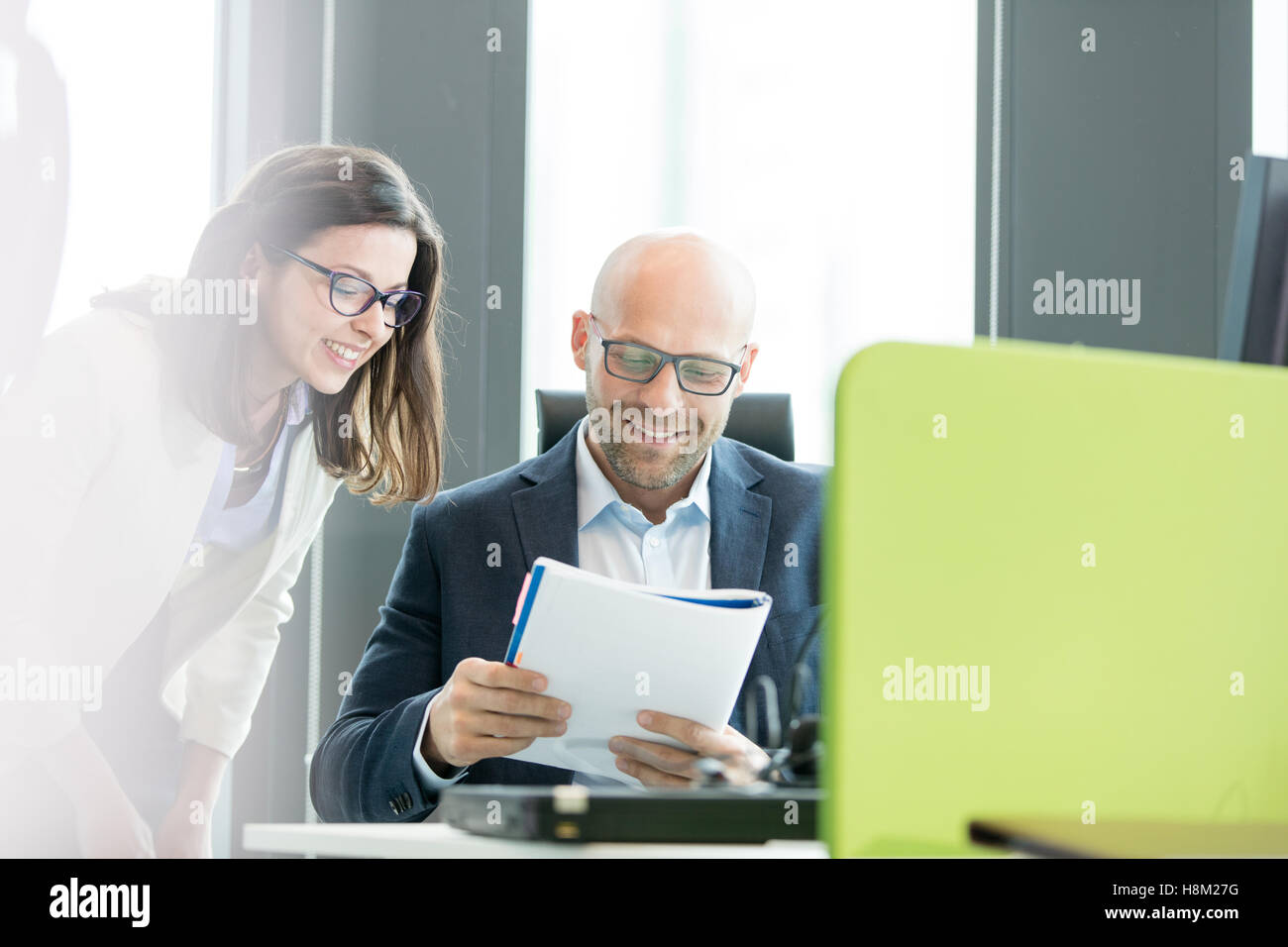 Imprenditrice sorridente e imprenditore libro in ufficio Foto Stock