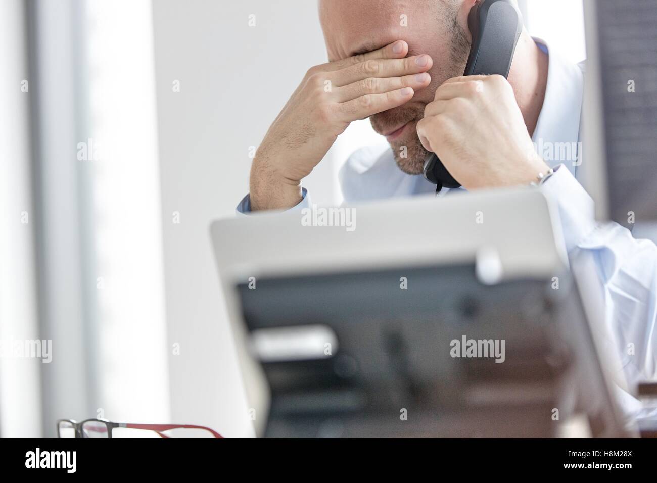 Imprenditore esausto tramite telefono fisso in ufficio Foto Stock