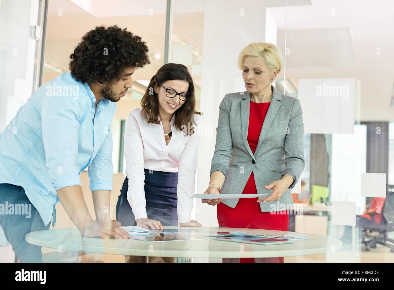 Imprenditrice maturo con i colleghi per discutere su progetto a tavola in ufficio Foto Stock