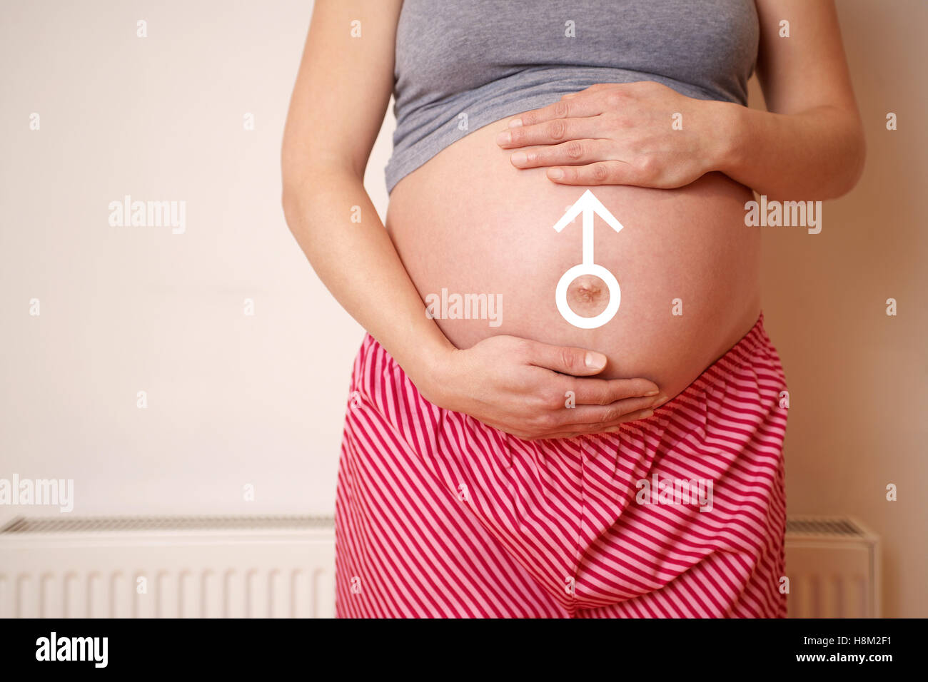 Sezione mediana di una donna in attesa di toccare la pancia mentre in piedi contro la parete Foto Stock