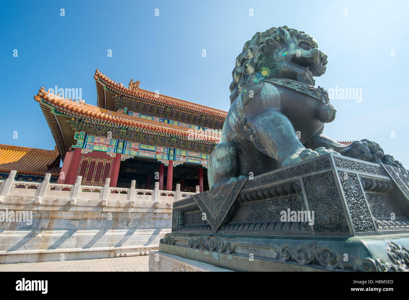 Pechino Cina - il Dettaglio di un bronzo guardian lion statua (SHI) con l'architettura ornata di il museo del palazzo in backg Foto Stock