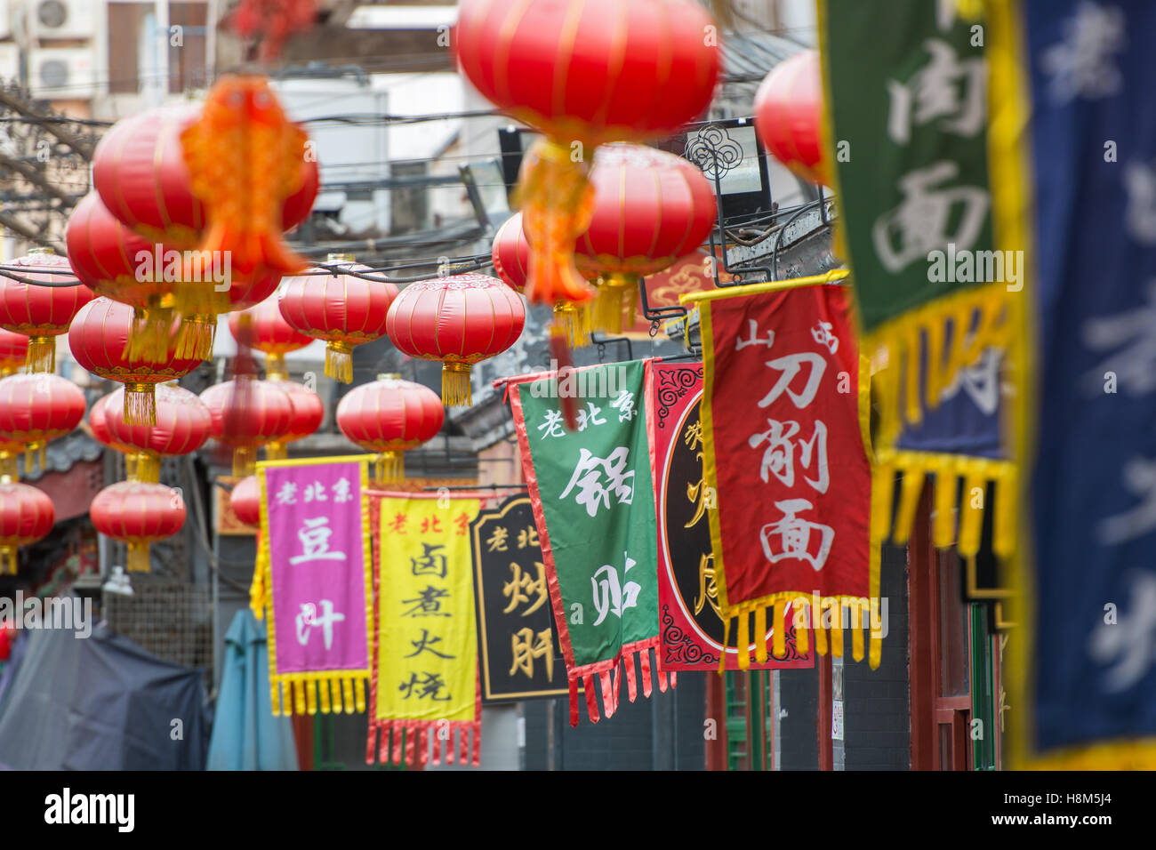 Pechino, Cina - bandiere colorate con i caratteri cinesi e lanterne appese in la Donghuamen Snack mercato notturno, una grande superarvi Foto Stock