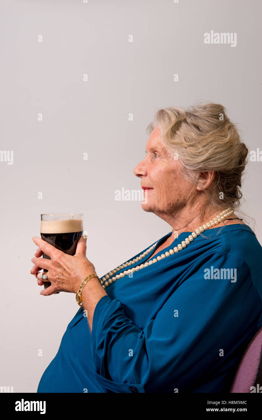 Un ritratto di una signora anziana tenendo una pinta di stout. Foto Stock