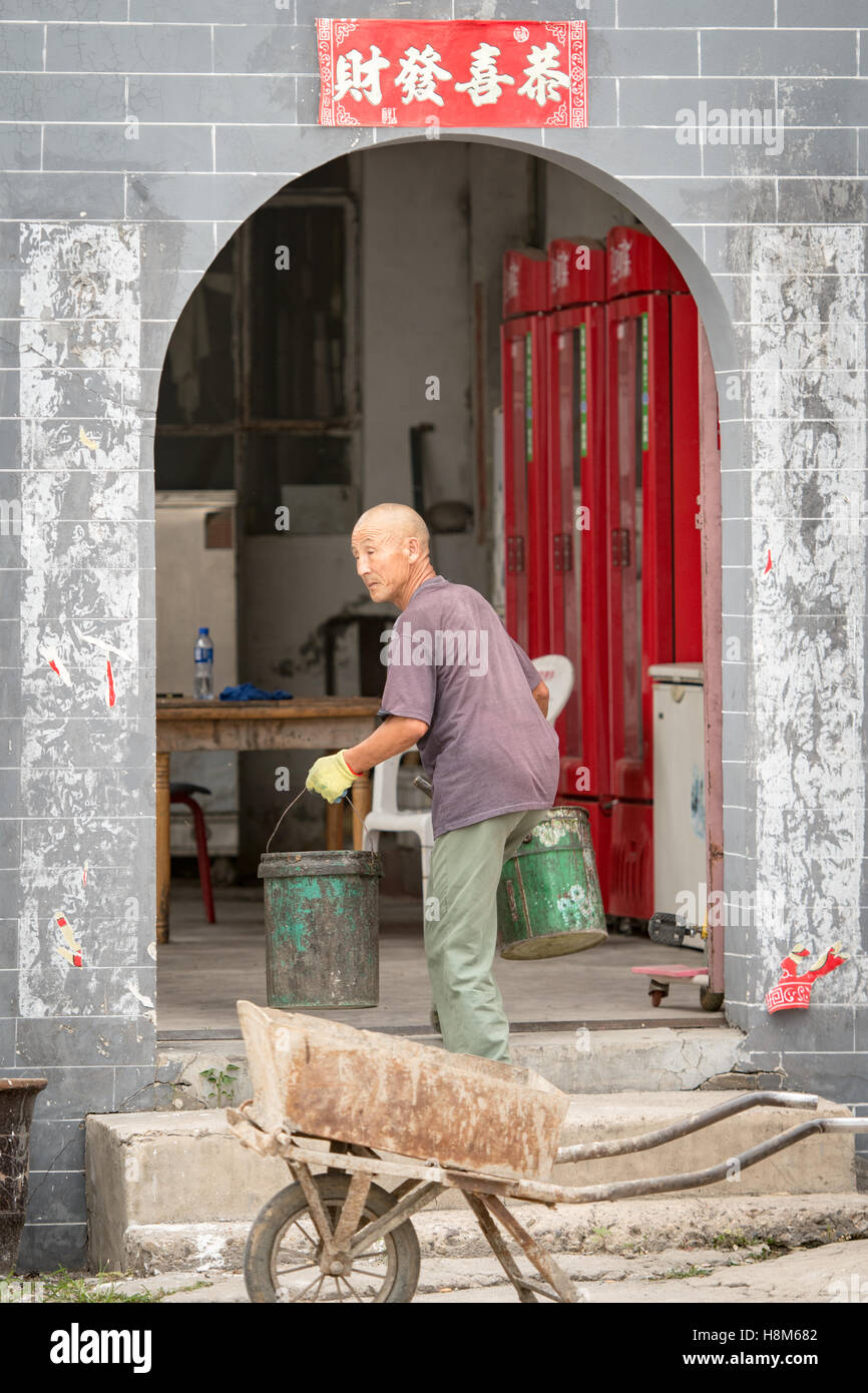 Pechino, Cina - un anziano uomo cinese che porta tazze in una fabbrica CloisonnŽ vicino a Pechino, in Cina. Foto Stock