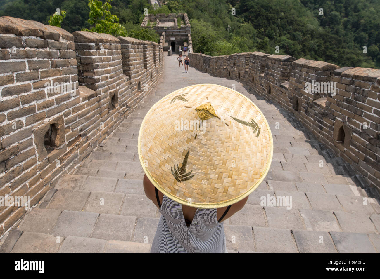 Mutianyu, Cina - Close up di una donna che indossa un asiatico cappello conico con turisti fotografare e camminando sulla Grande Muraglia o Foto Stock