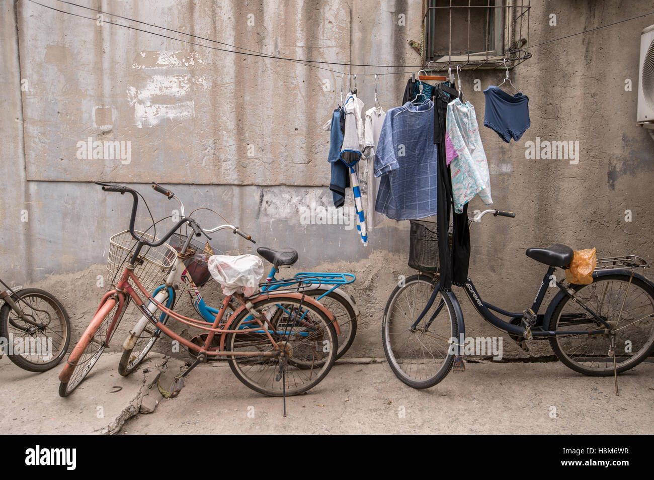 Pechino, Cina - Biciclette parcheggiate e panni appesi ad asciugare al di fuori di una piccola casa in un hutong situato nel centro di Pechino. Foto Stock