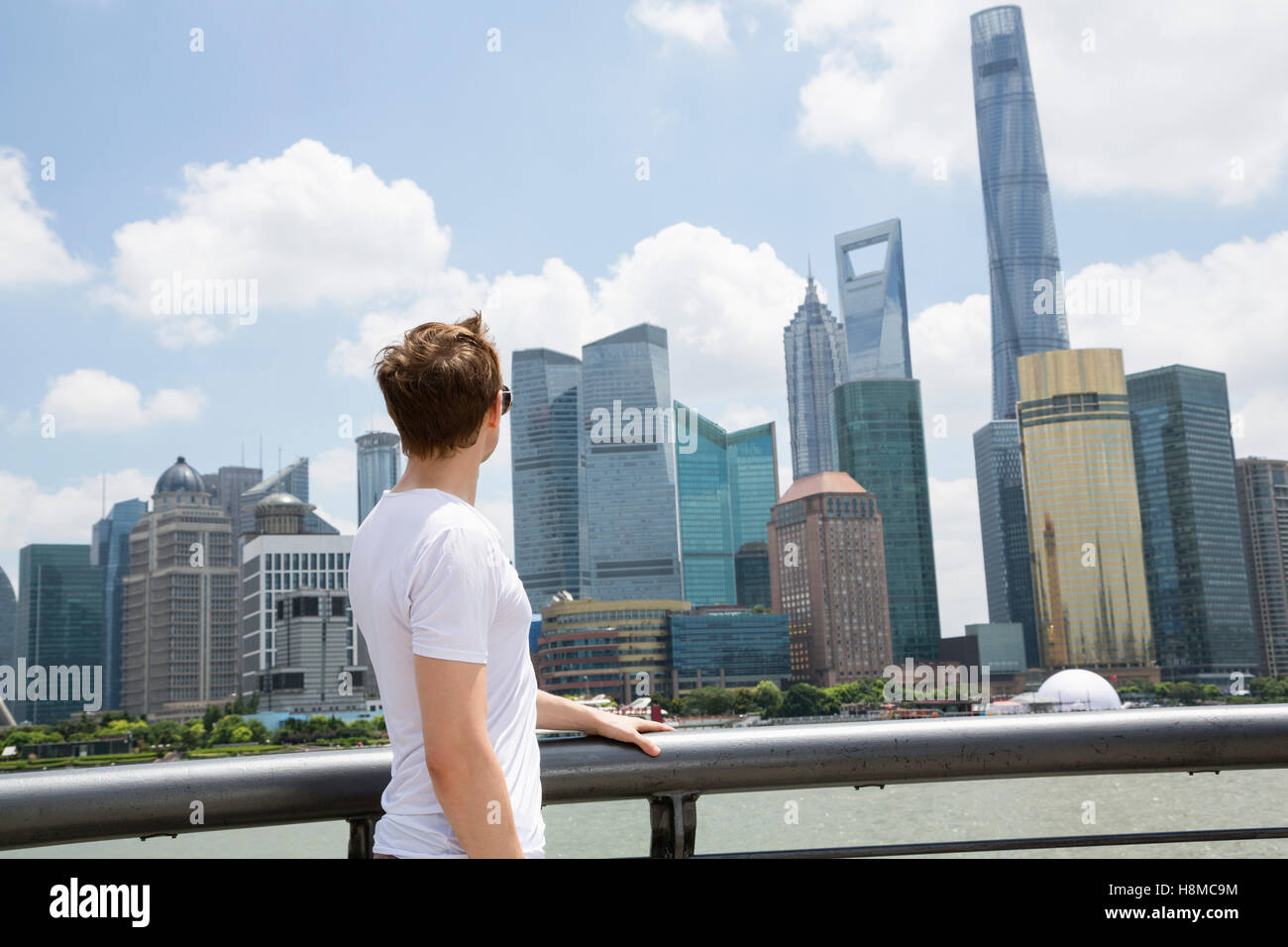 Vista laterale di un uomo guarda il World Financial Center di Shanghai contro il cielo nuvoloso Foto Stock
