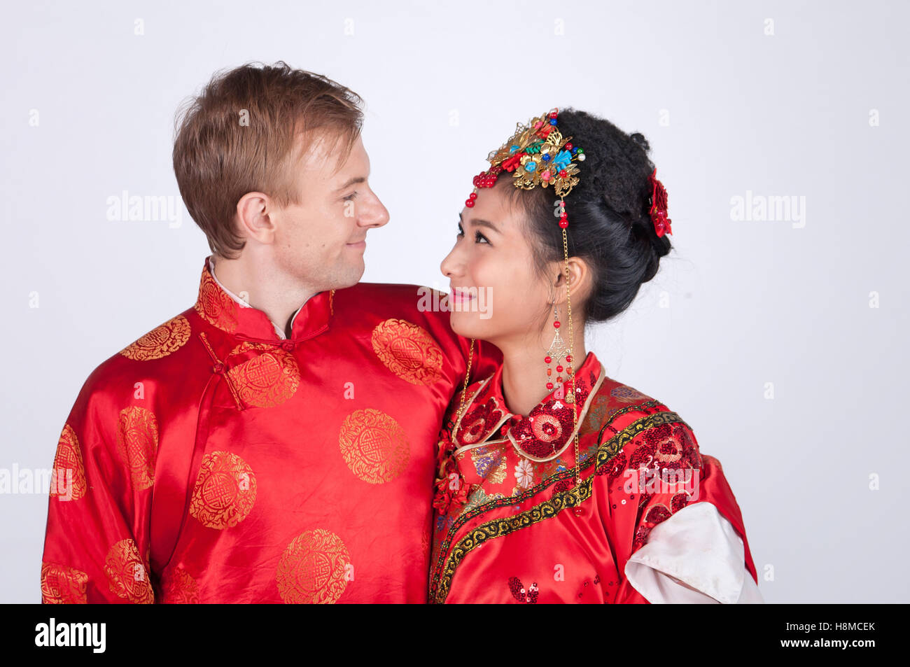 Razza mista sposa e lo sposo in Studio indossando il tradizionale cinese corredi nuziali Foto Stock