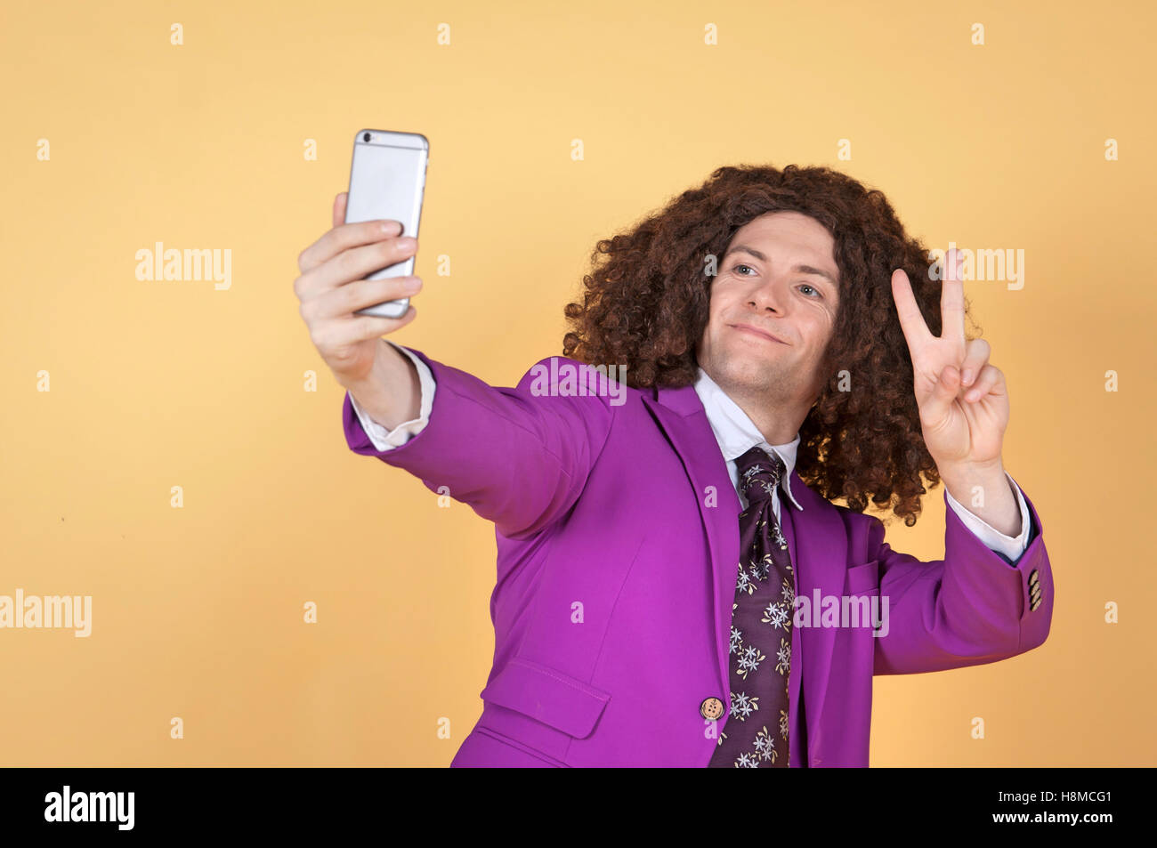 Uomo caucasico con Afro indossa vestito viola prendendo un selfie Foto Stock