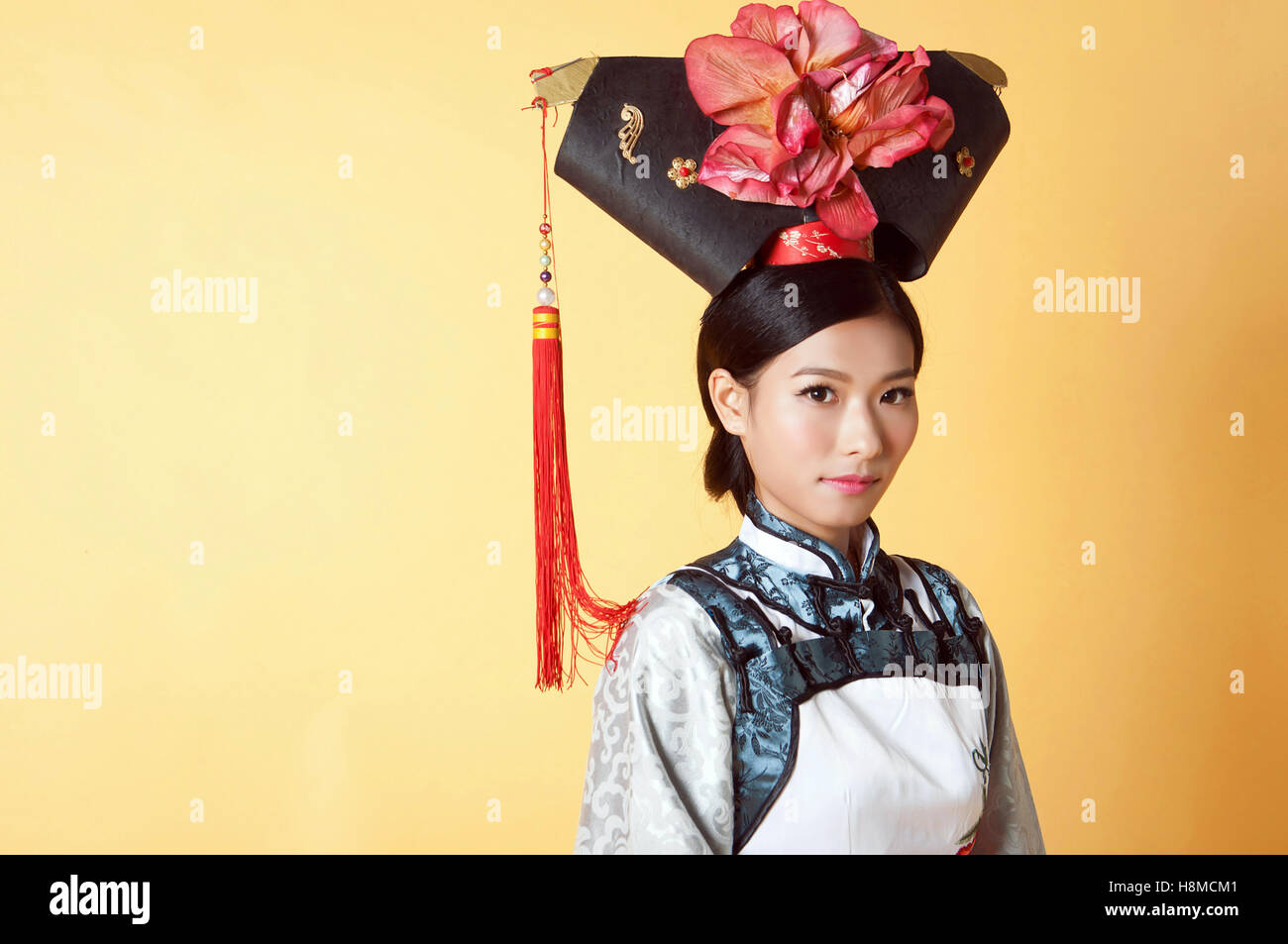 Bella donna cinese che indossa il vestito tradizionale contro sfondo giallo Foto Stock