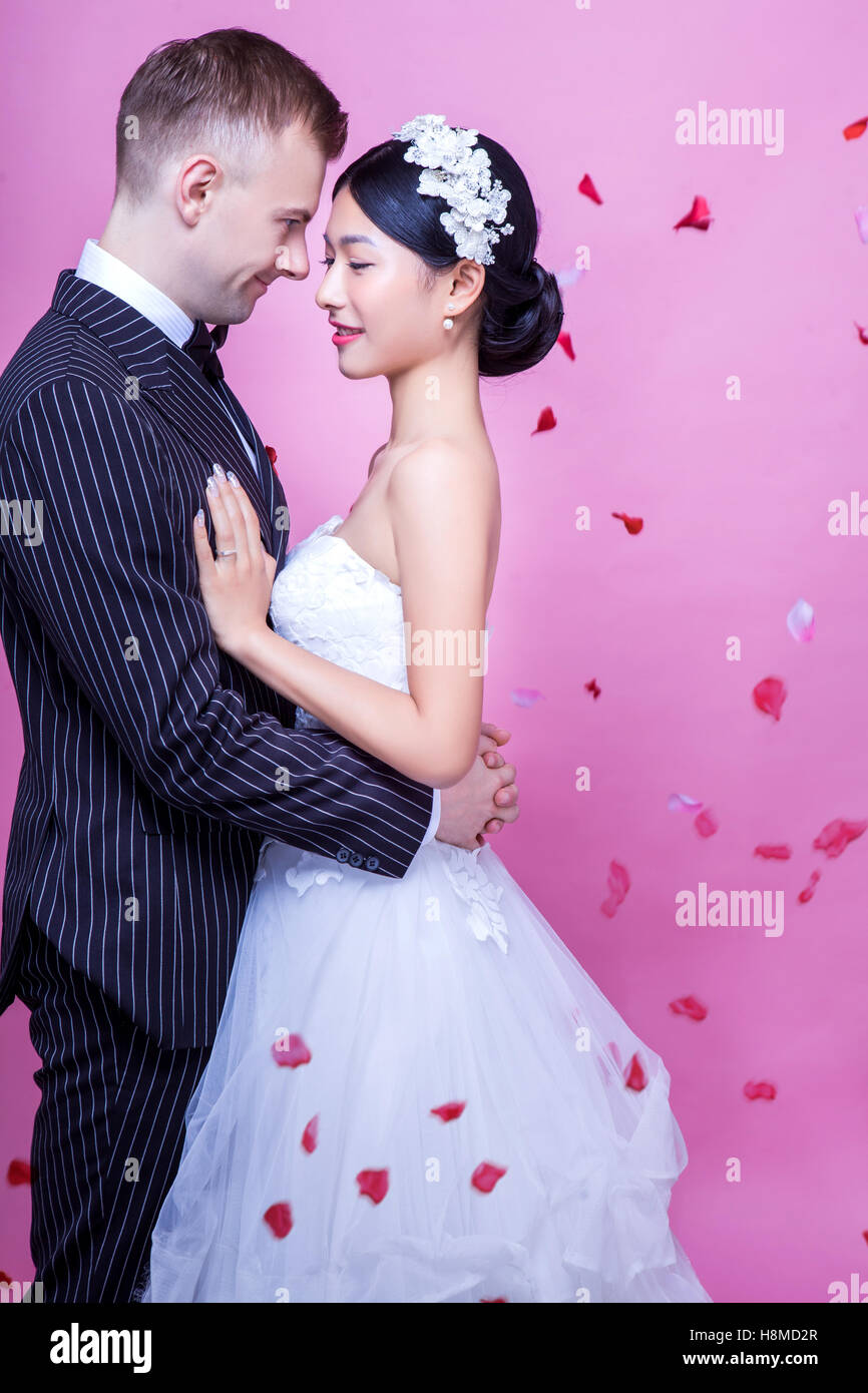 Vista laterale del matrimonio romantico giovane abbracciando contro sfondo rosa Foto Stock