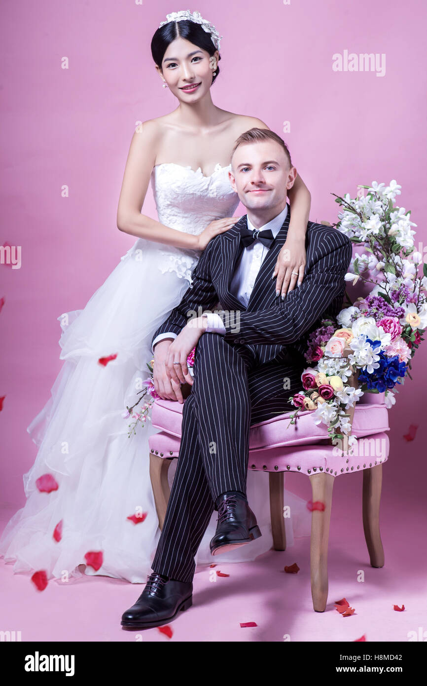 Ritratto di nozze elegante giovane seduto contro sfondo rosa Foto Stock