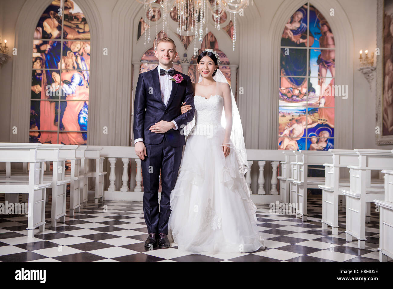 Ritratto di certi sposi in piedi a braccetto in chiesa Foto Stock