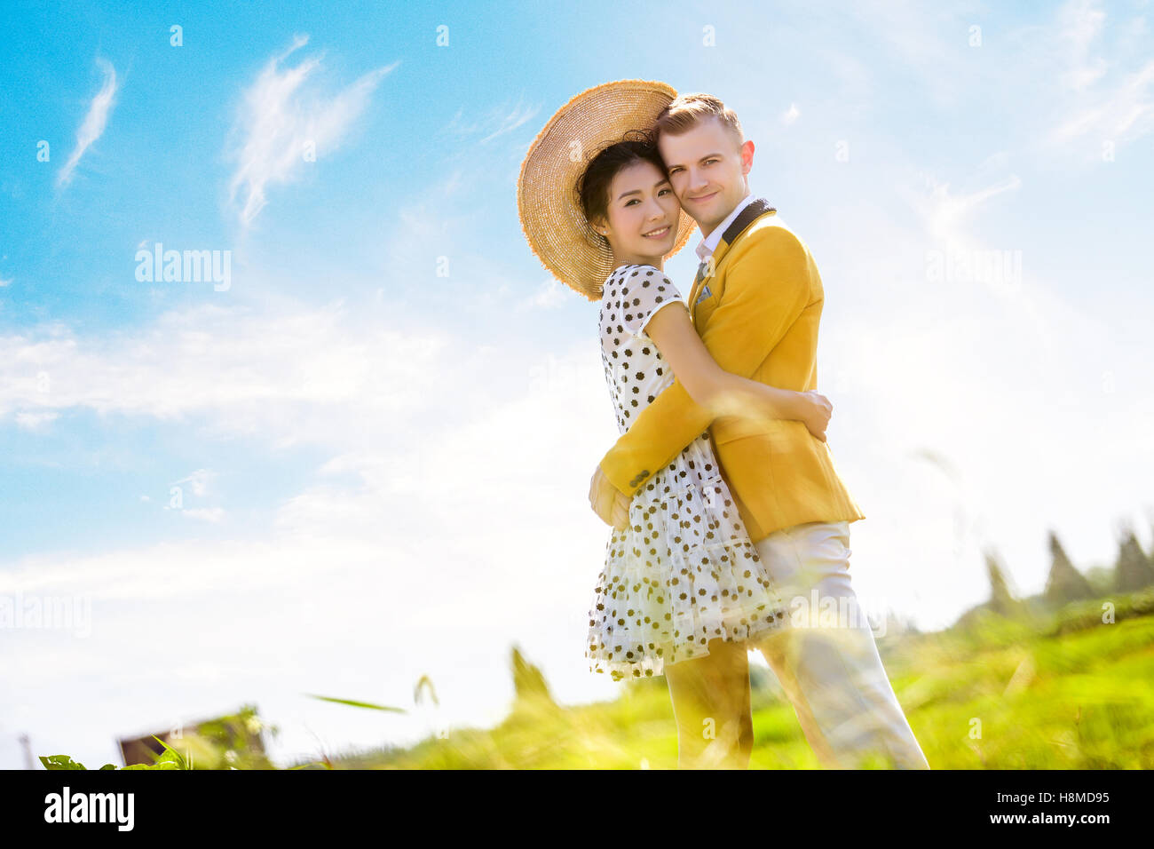 Vista laterale ritratto della coppia romantica abbracciando sul campo contro sky Foto Stock