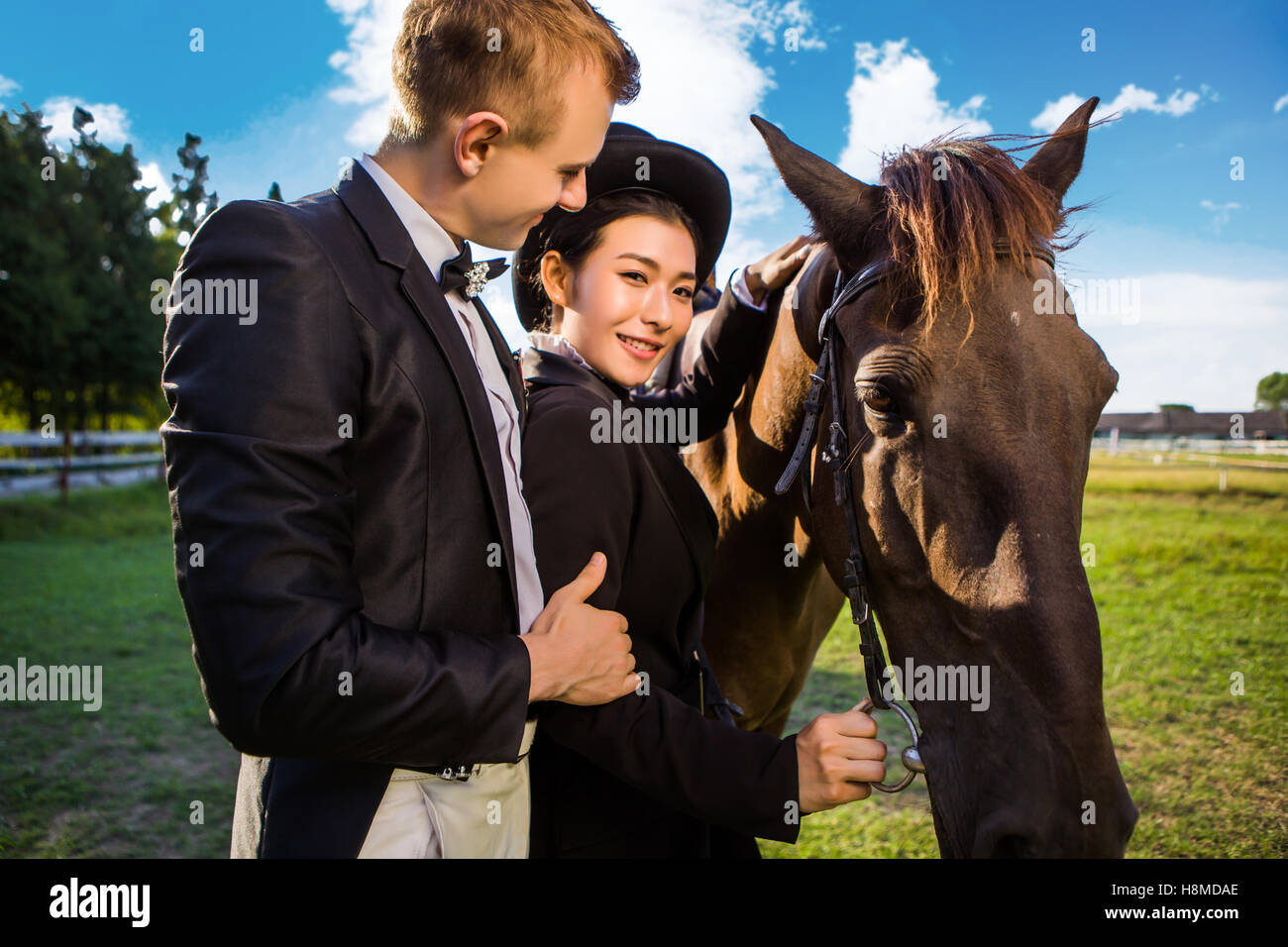 Ritratto di donna sorridente in piedi con uomo a cavallo sul campo Foto Stock