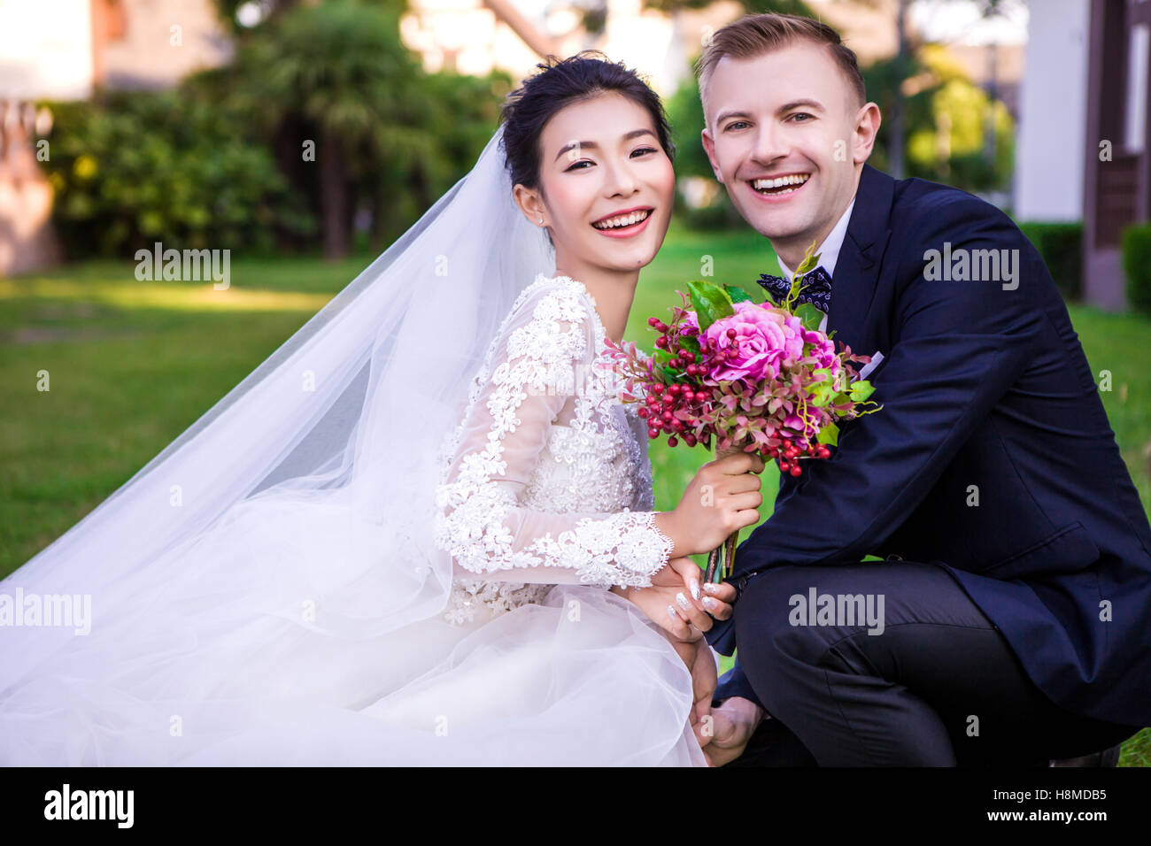 Ritratto di felice matrimonio giovane accovacciato a prato Foto Stock