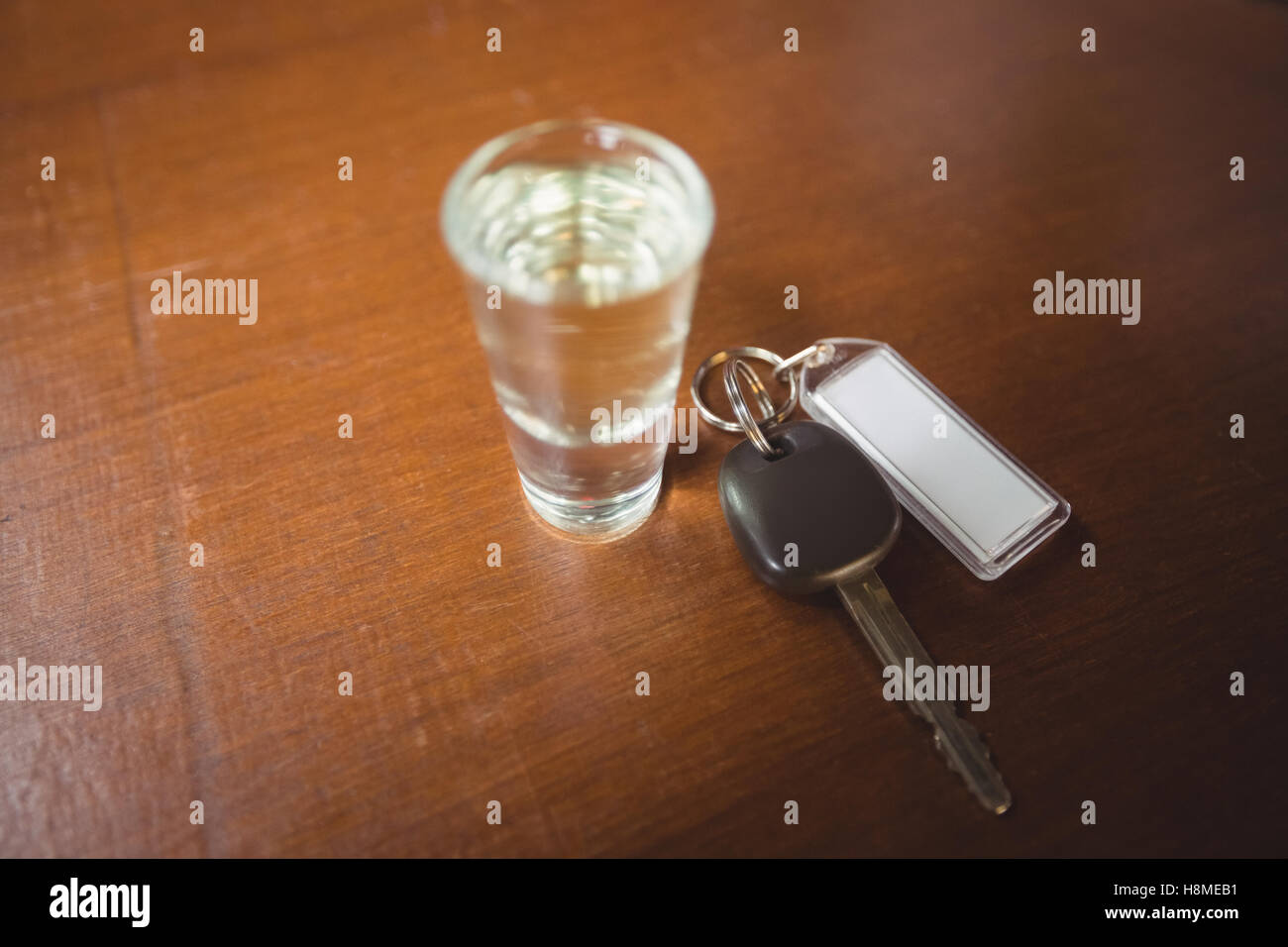 Bicchiere di tequila shot con chiave auto nel bancone bar Foto Stock