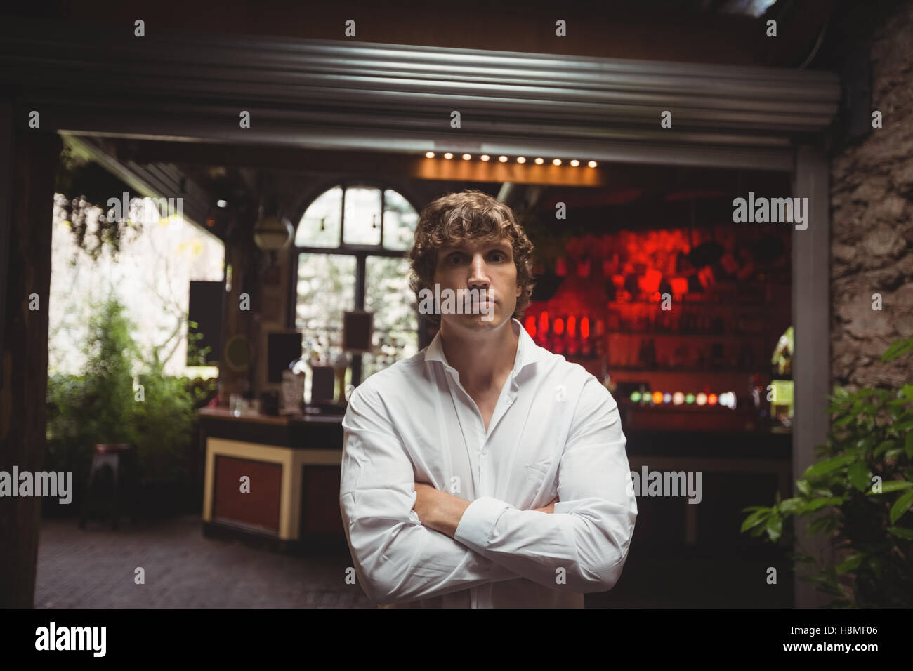 Uomo in piedi con le braccia incrociate in bar Foto Stock