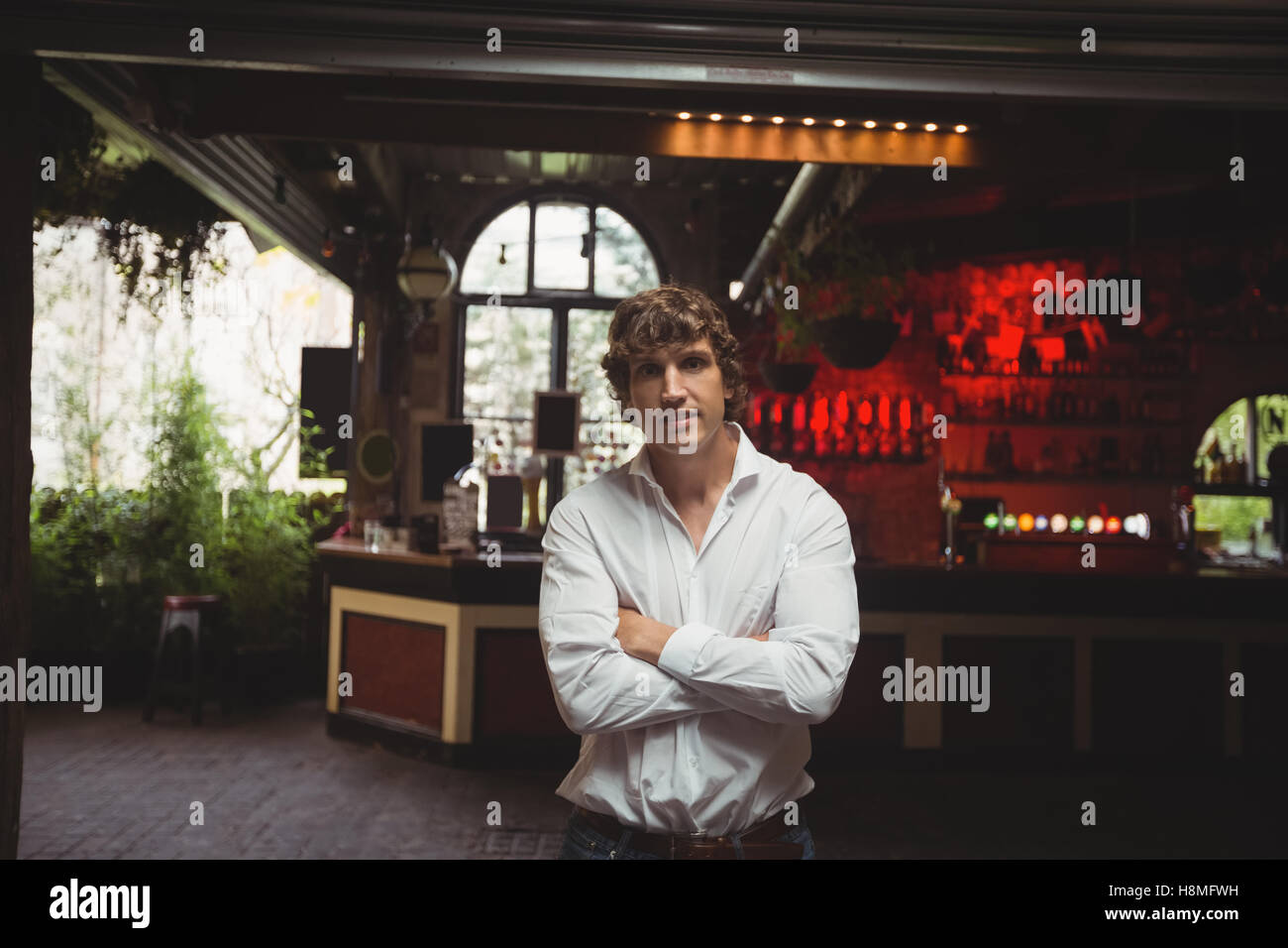 Uomo in piedi con le braccia incrociate in bar Foto Stock