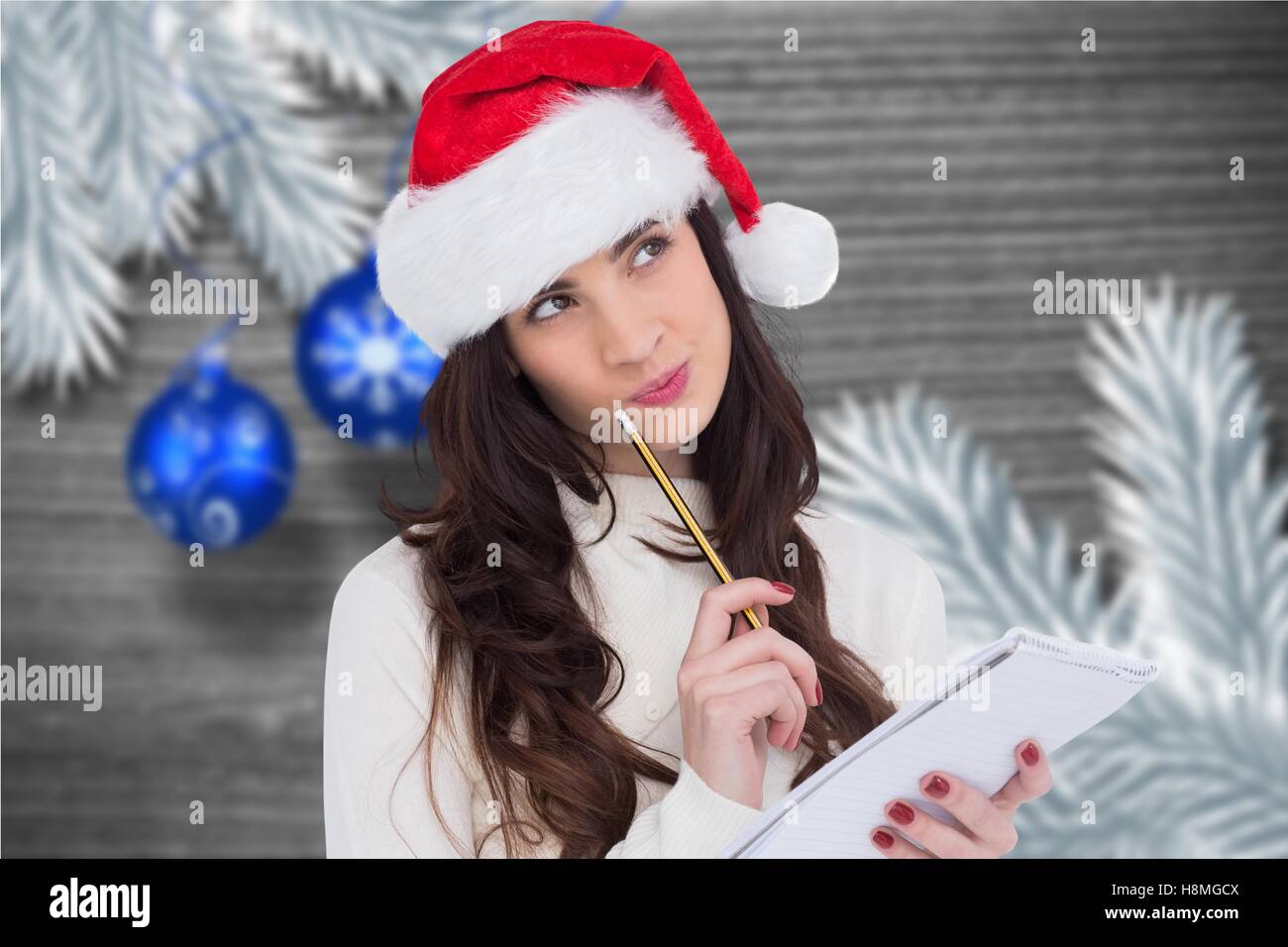 Premurosa donna in santa hat facendo una lista dei desideri Foto Stock