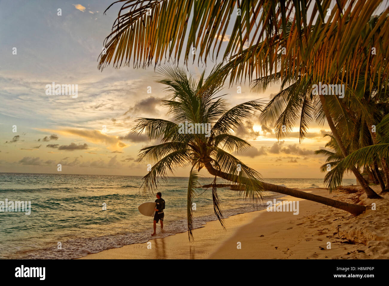 Surfer e tramonto a Dover Beach, St. Lawrence Gap, costa sud di Barbados, dei Caraibi. Foto Stock